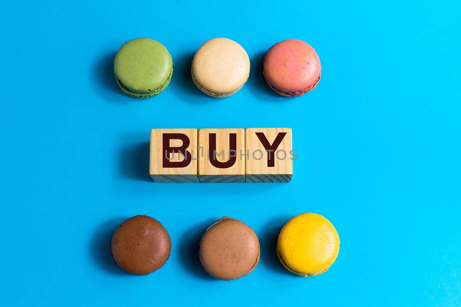 Colorful cake macaron or macaroon on a blue background. Flat lay, top view, copy space. Word Buy