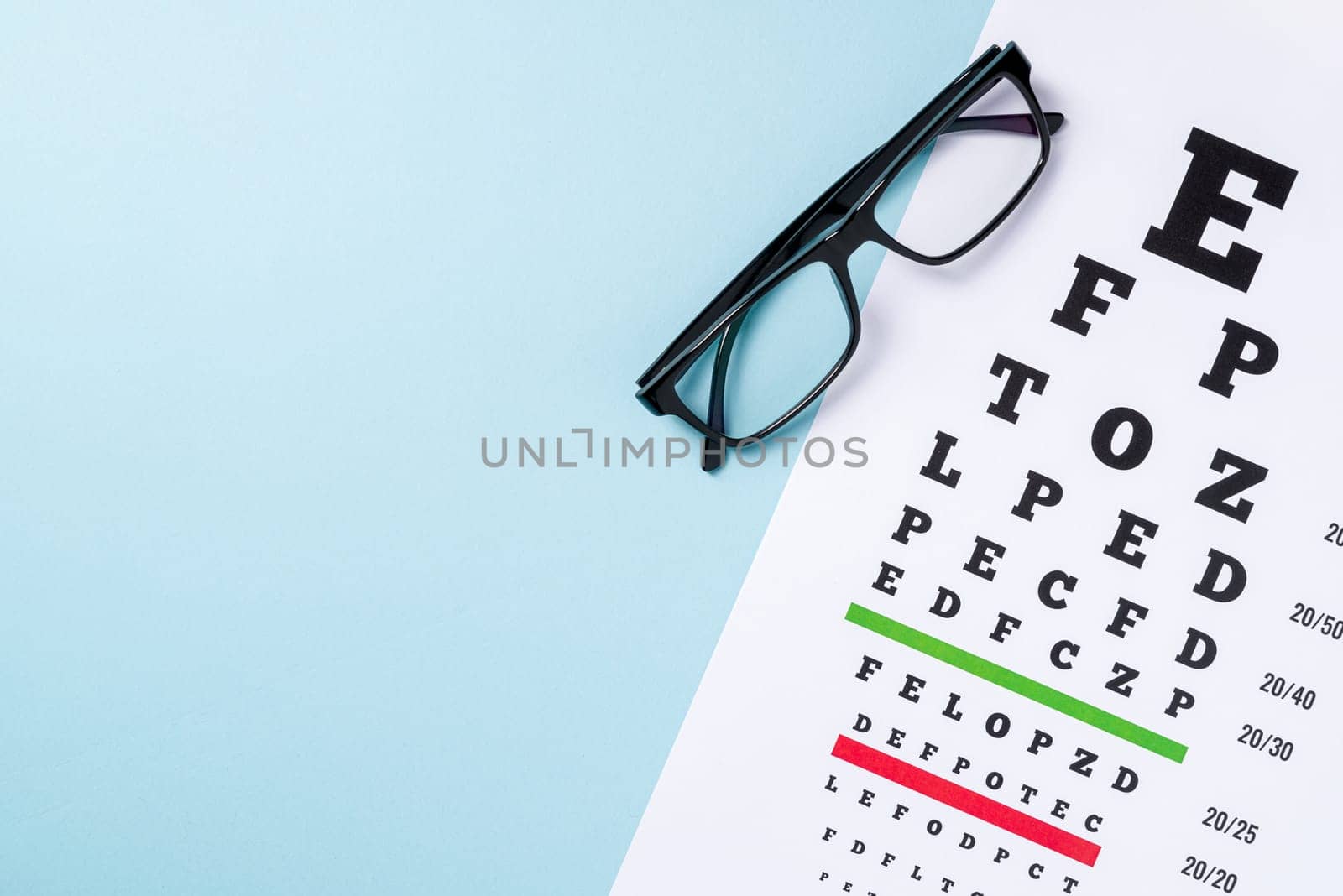 Eye test chart and glasses on blue background by Sonat