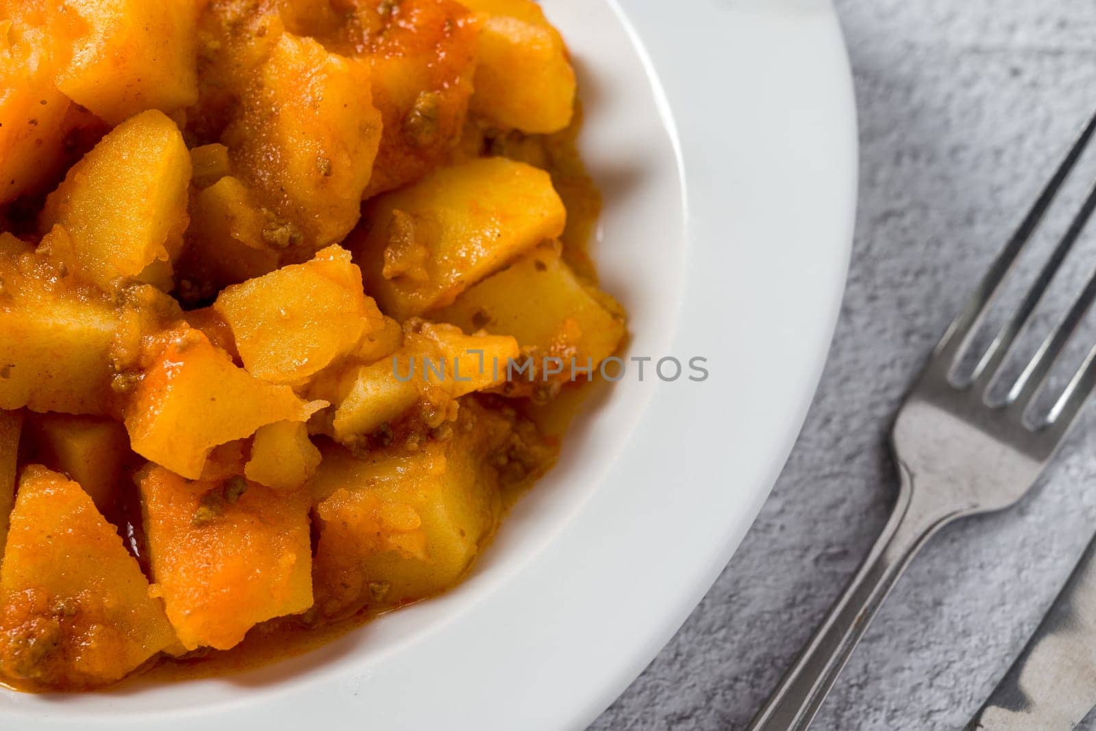 Minced meat and potato dish on white porcelain plate on stone table by Sonat