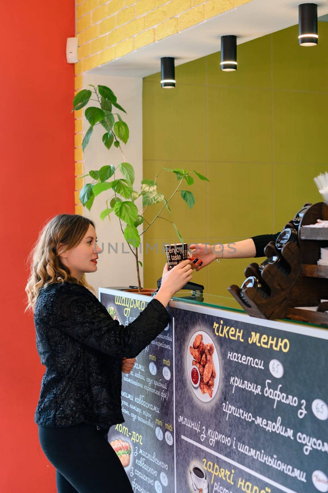Ivano-Frankivsk, Ukraine March 26, 2023: A woman orders coffee at a cafe, a small fast-food restaurant.