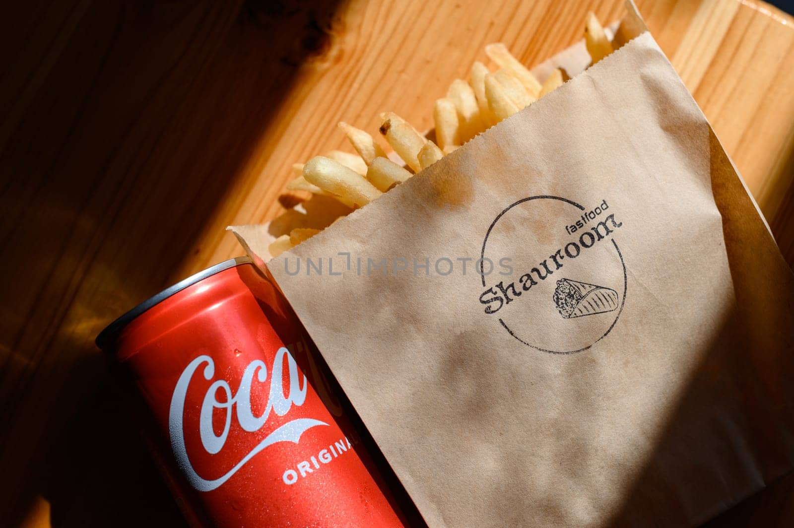 Ivano-Frankivsk, Ukraine March 26, 2023: Coca Cola and french fries in a paper bag on a black background.