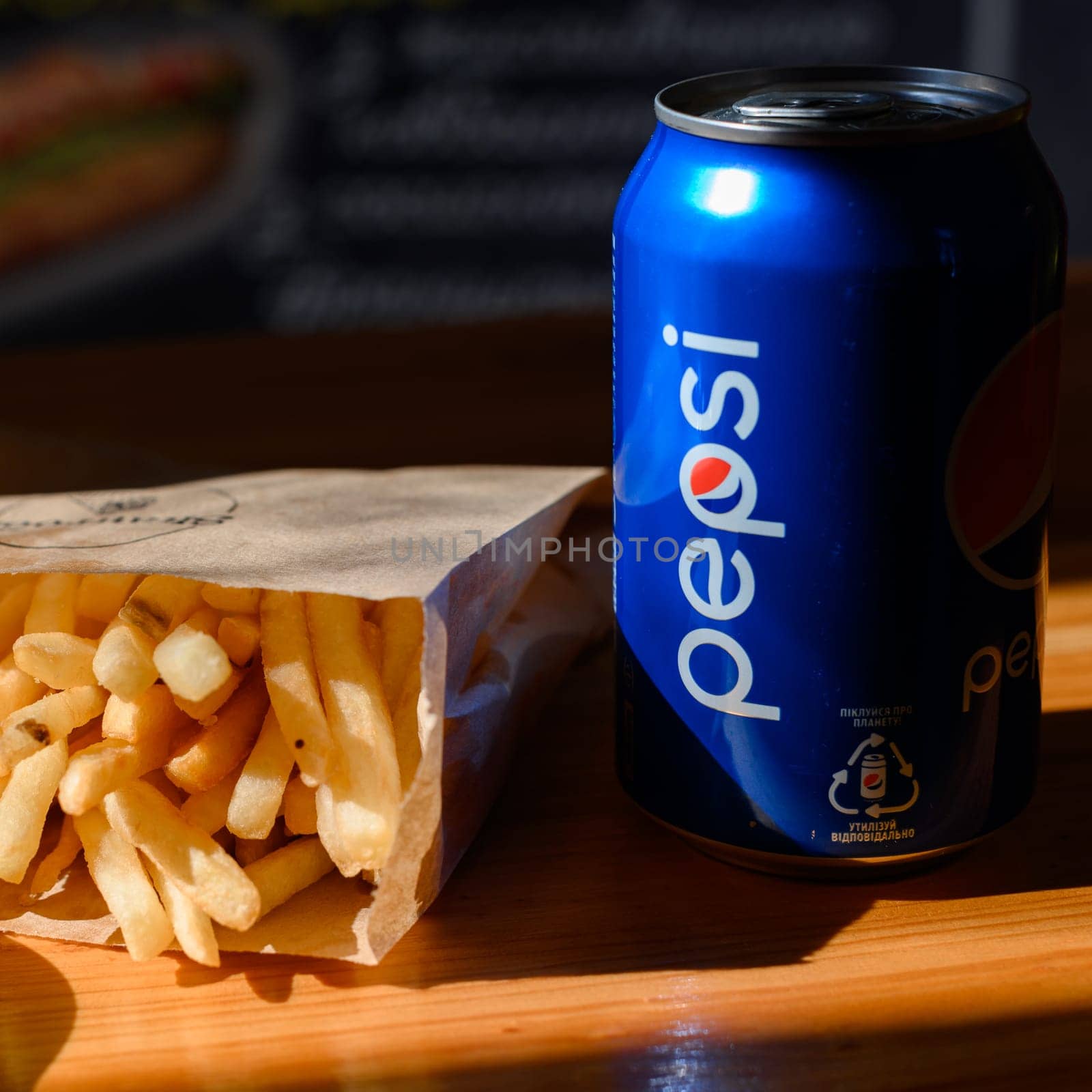 Ivano-Frankivsk, Ukraine March 26, 2023: Pepsi and french fries in a paper bag. by Niko_Cingaryuk