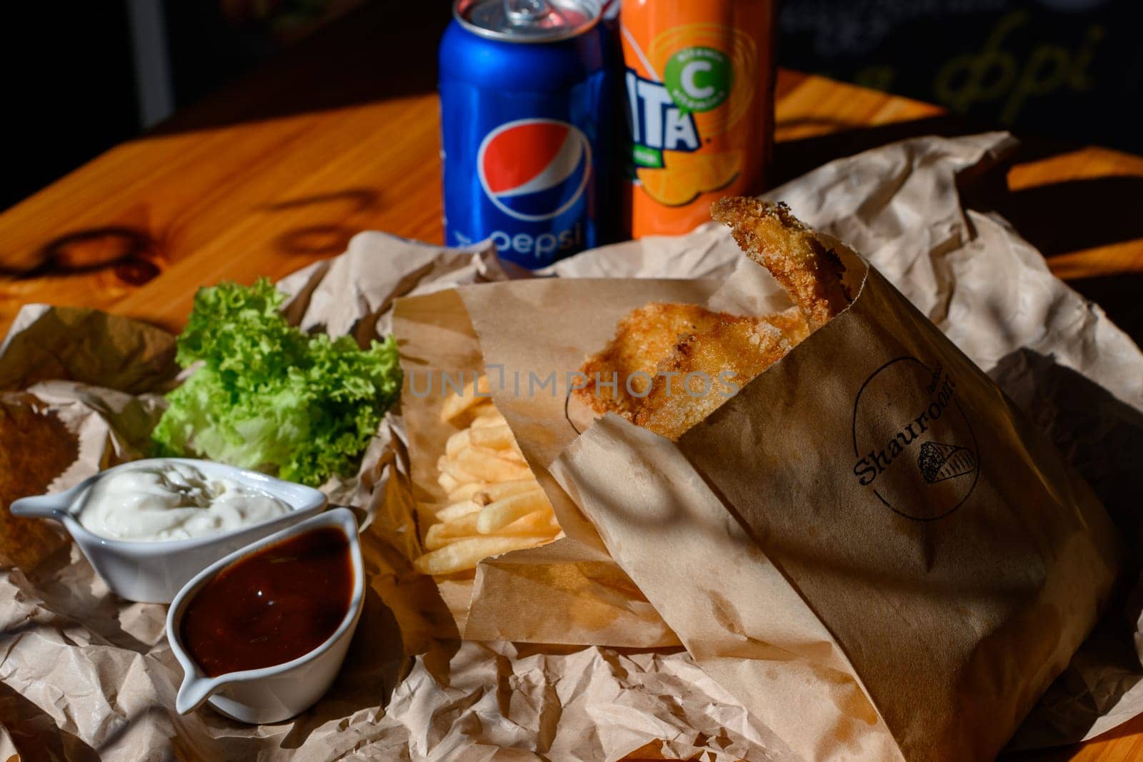 Ivano-Frankivsk, Ukraine March 26, 2023: three bottles of coke, fanta and pepsi with chicken nuggets and french fries on the table, fatty and unhealthy food.