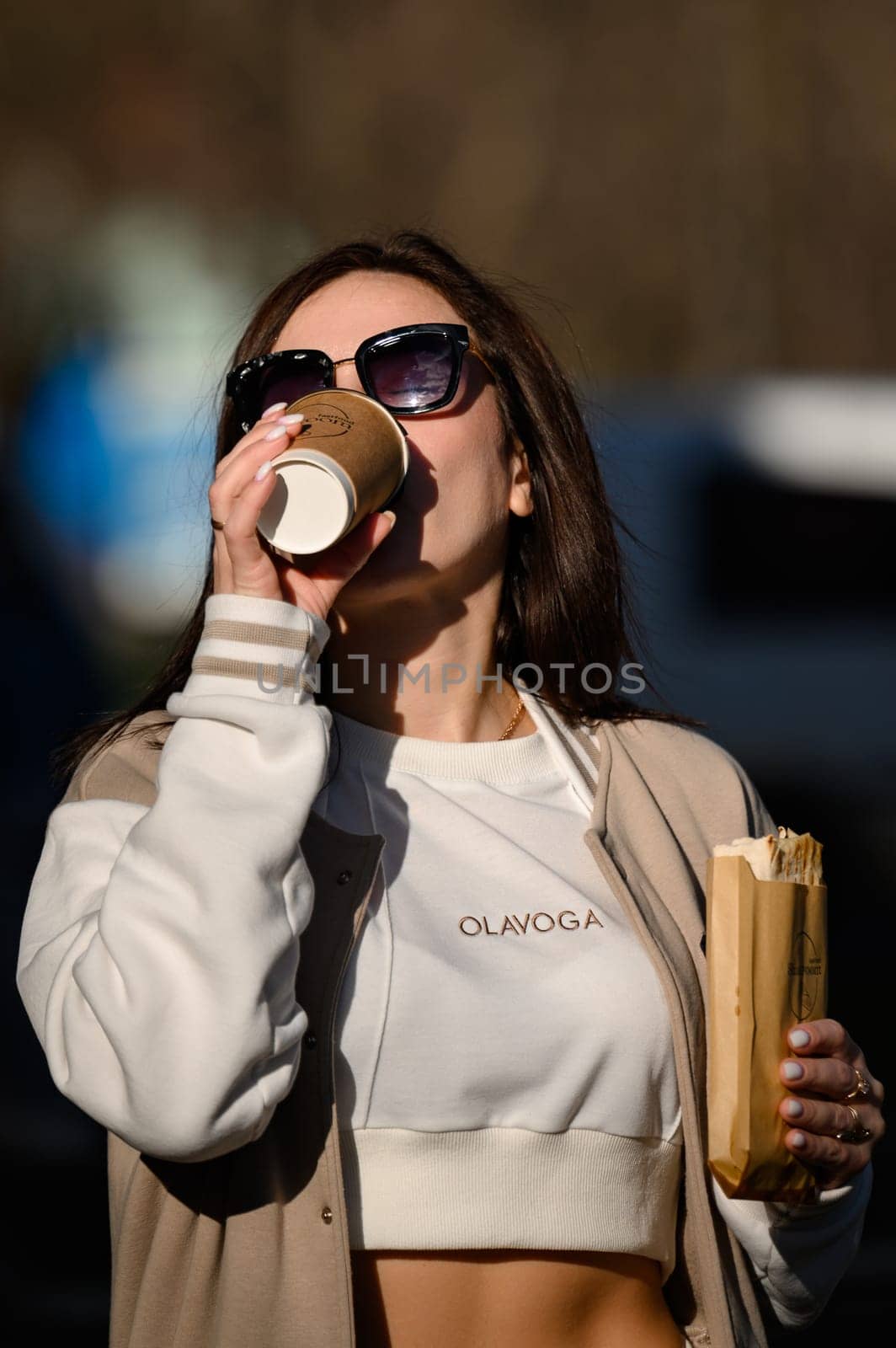 Ivano-Frankivsk, Ukraine March 26, 2023: Photo of a girl with shawarma and coffee on the street, a quick snack on the street.