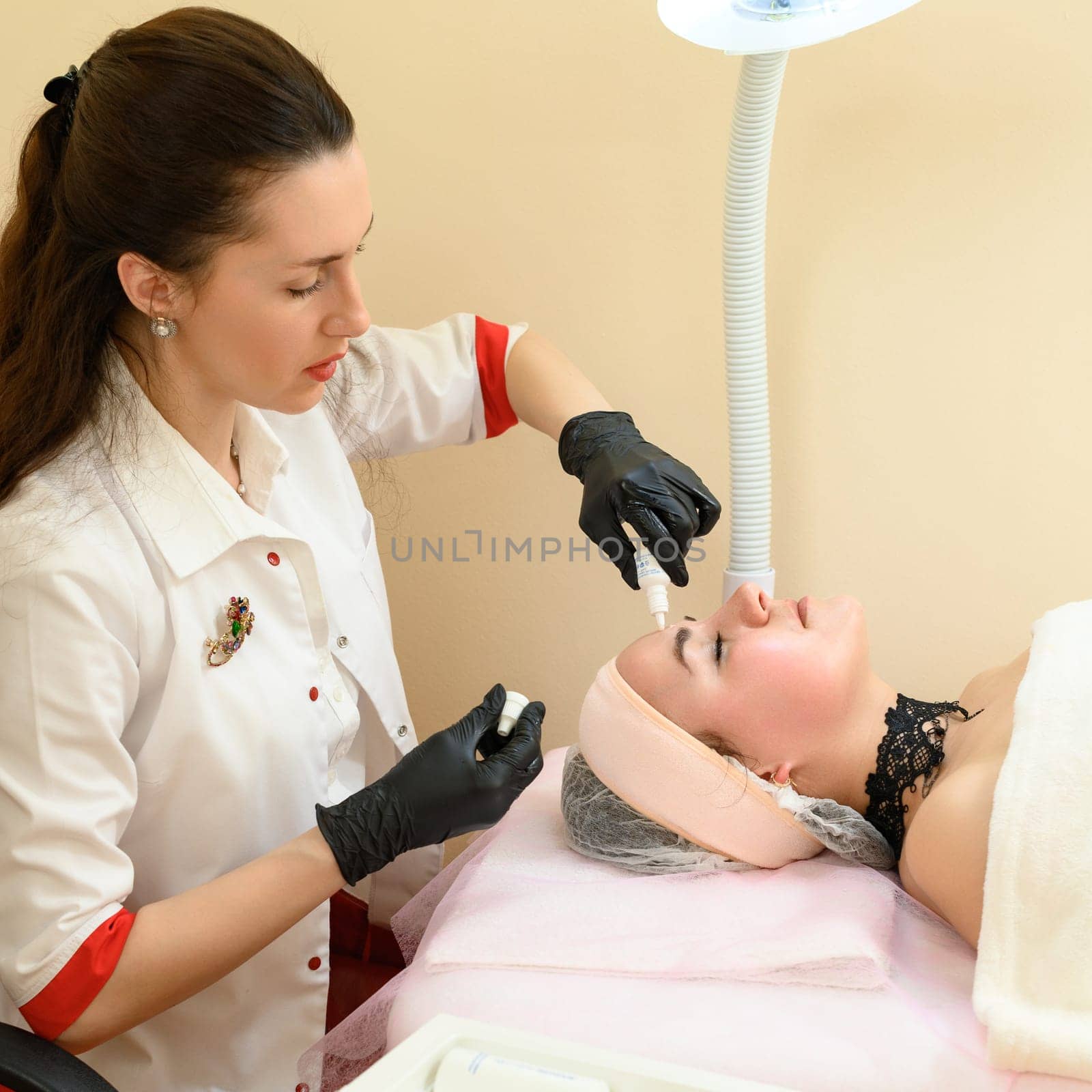 Ivano-Frankivsk, May 17, 2023: A cosmetologist applies couperosis cream to a girl's face, a procedure to reduce couperosis on the face.