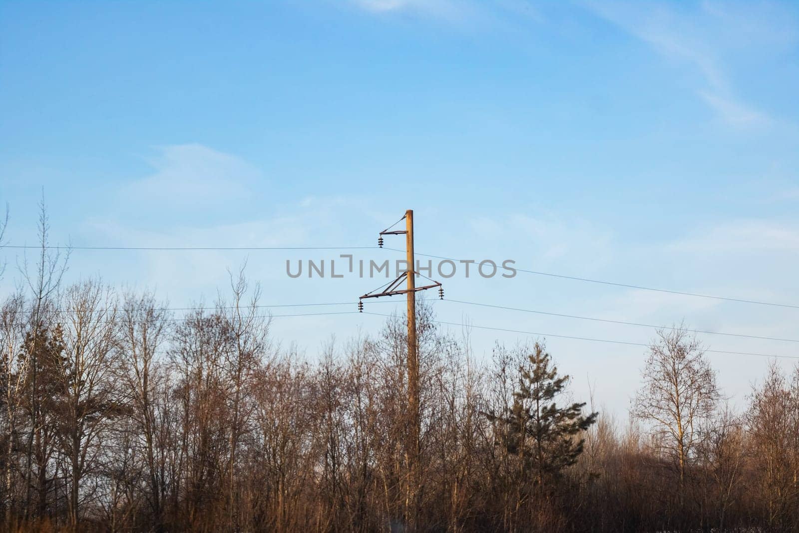 A pole with electric wires against a blue sky, copy space