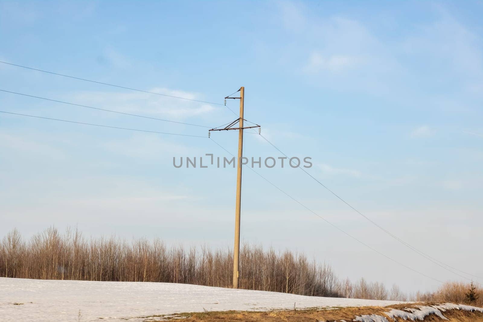 A pole with electric wires against a blue sky, copy space