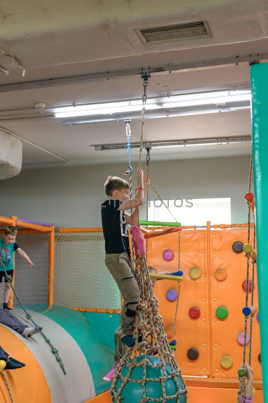 Ivano-Frankivsk, Ukraine June 7, 2023:A child rides on a rope over a pool of soft cubes, children's entertainment in a playroom.