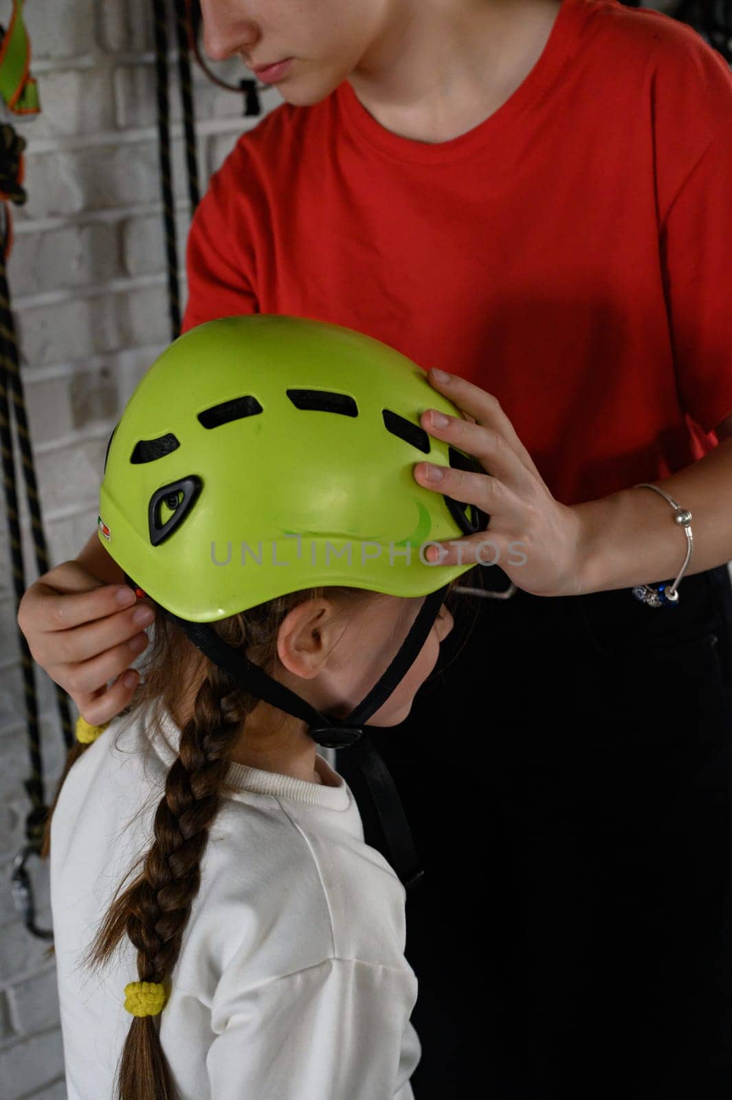A little girl is put on a helmet as protection on the cable car, the cable car in the playroom. Ivano-Frankivsk, Ukraine June 7, 2023