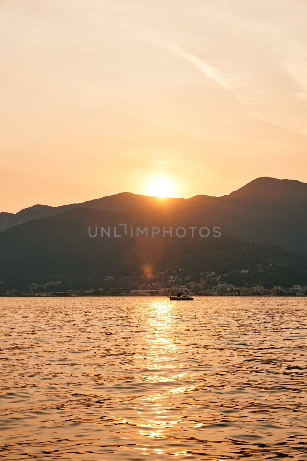 Sailing yacht sails on the sea against the backdrop of mountains at sunset. High quality photo