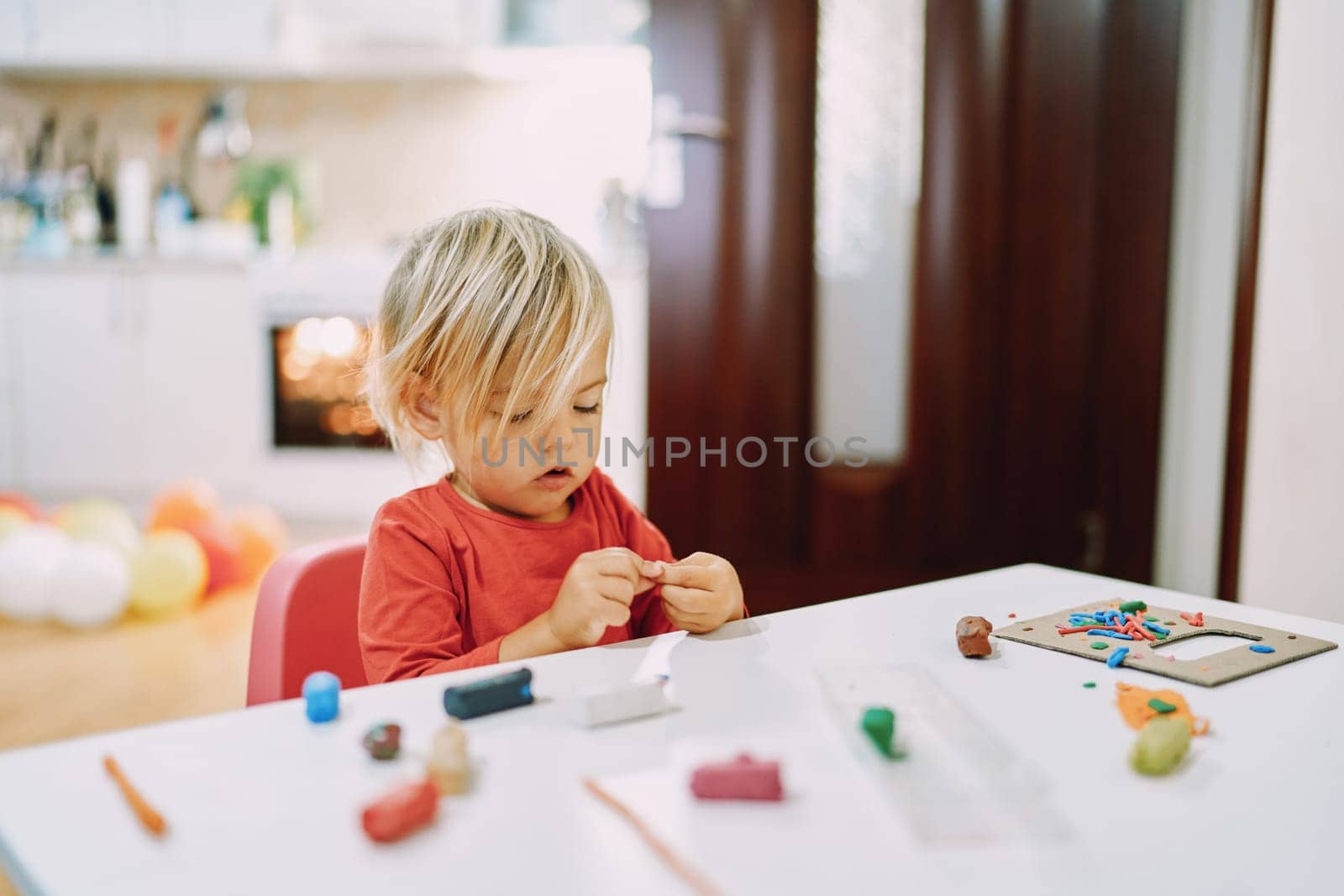 Little girl sits at a table and sculpts from plasticine. High quality photo