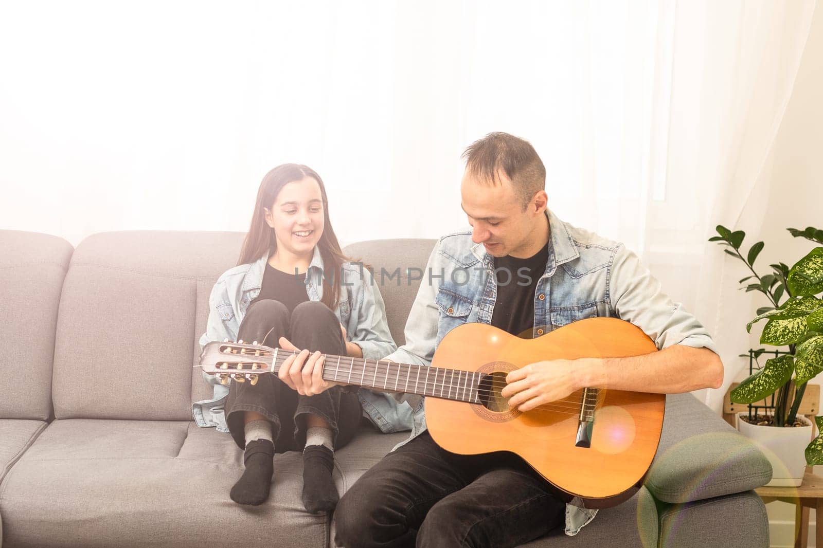 Artistic talented girl showing her latin music teacher the new song she learned to play on the acoustic guitar at home. High quality photo