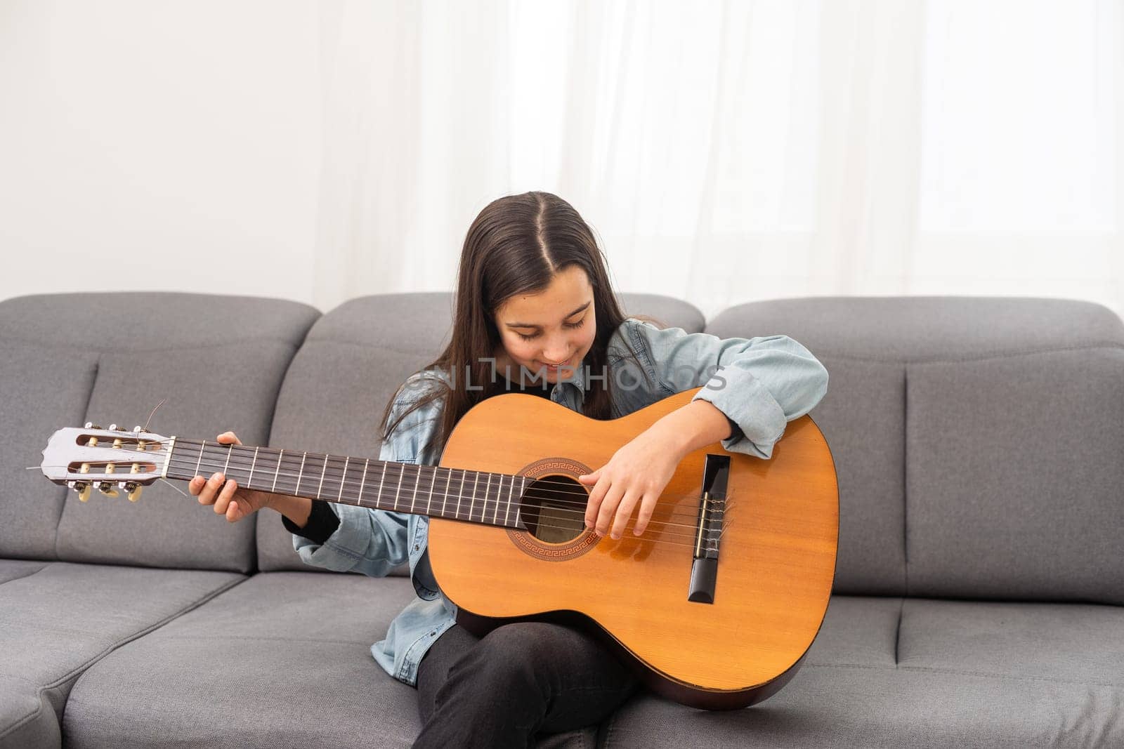beautiful young girl plays guitar at home. High quality photo