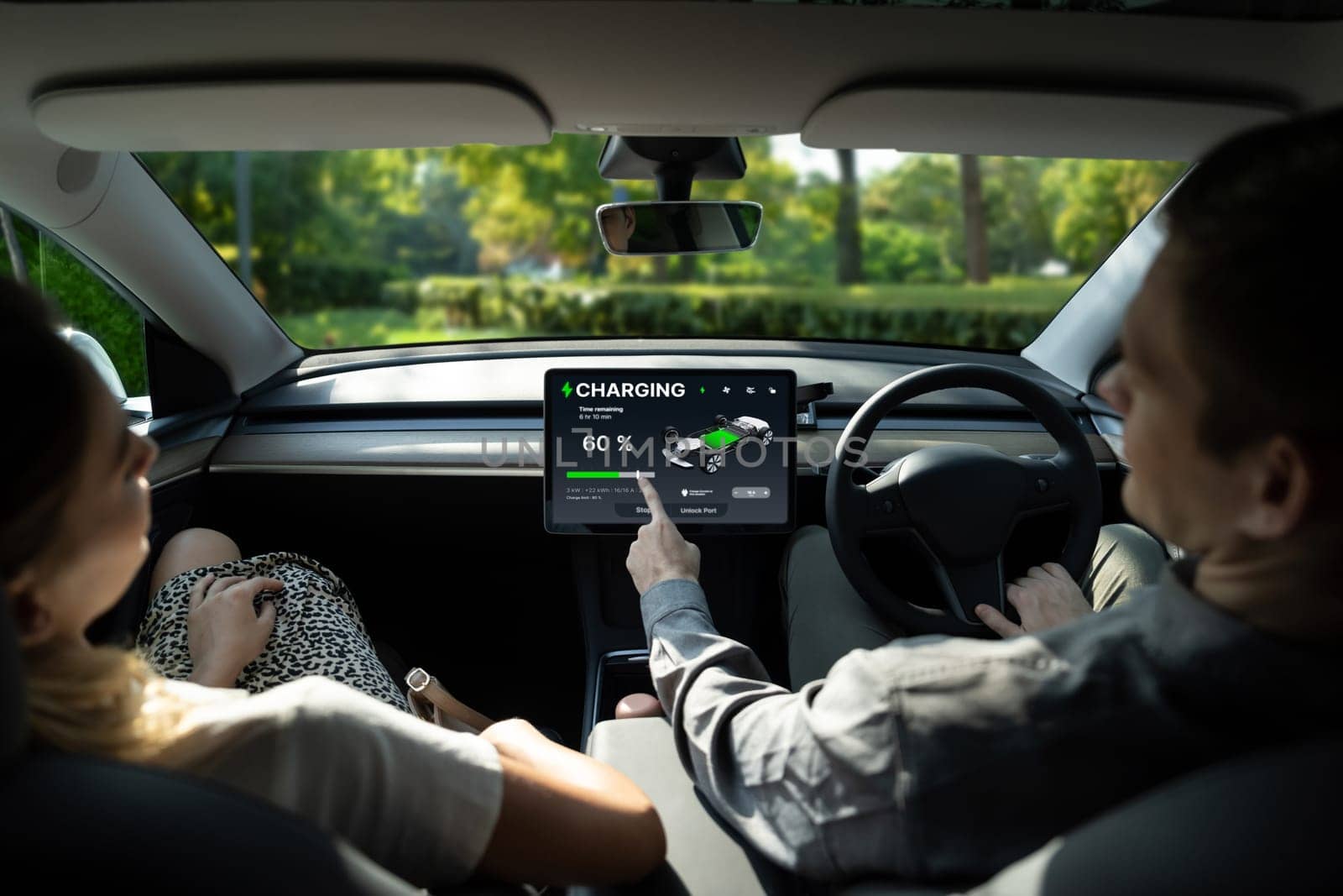 Electric car driver checks battery charging status, range and charging limit on app screen in the car. Smart technology device show EV car recharging data of electric storage in car battery innards.