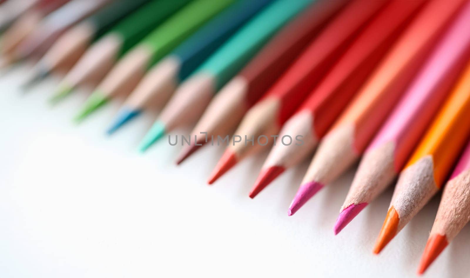 Many multicolored pencils lying on white background closeup. Sale of stationery concept