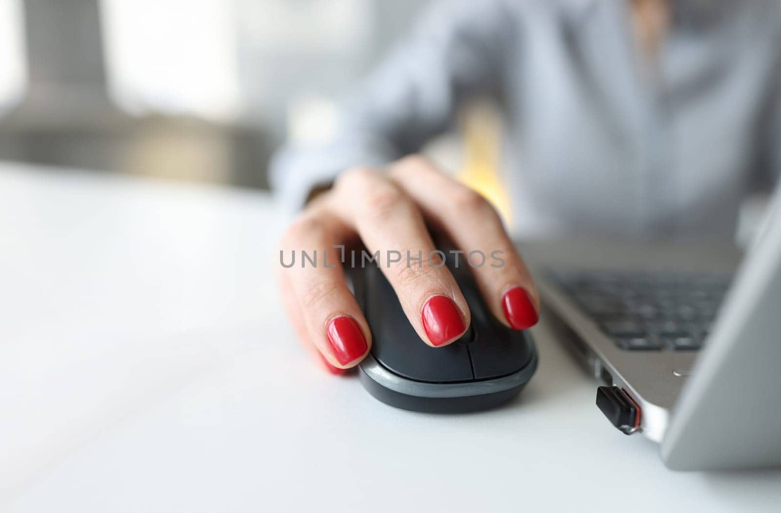 Woman with red manicure holding computer mouse near laptop closeup. Work online concept