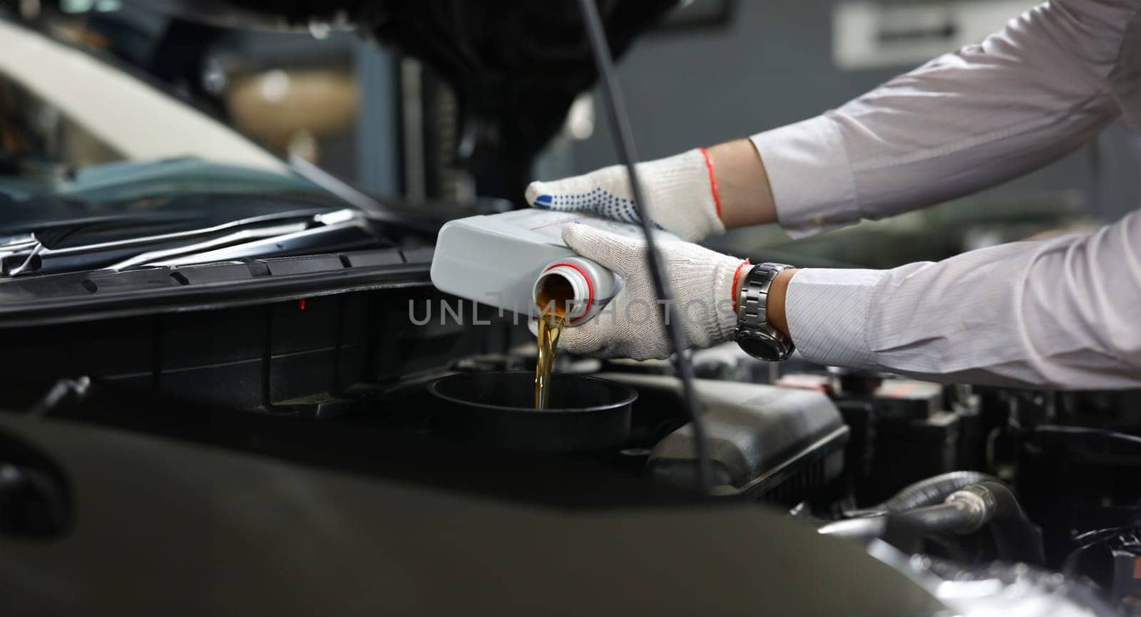 Foreman pours engine oil into engine. Car service concept