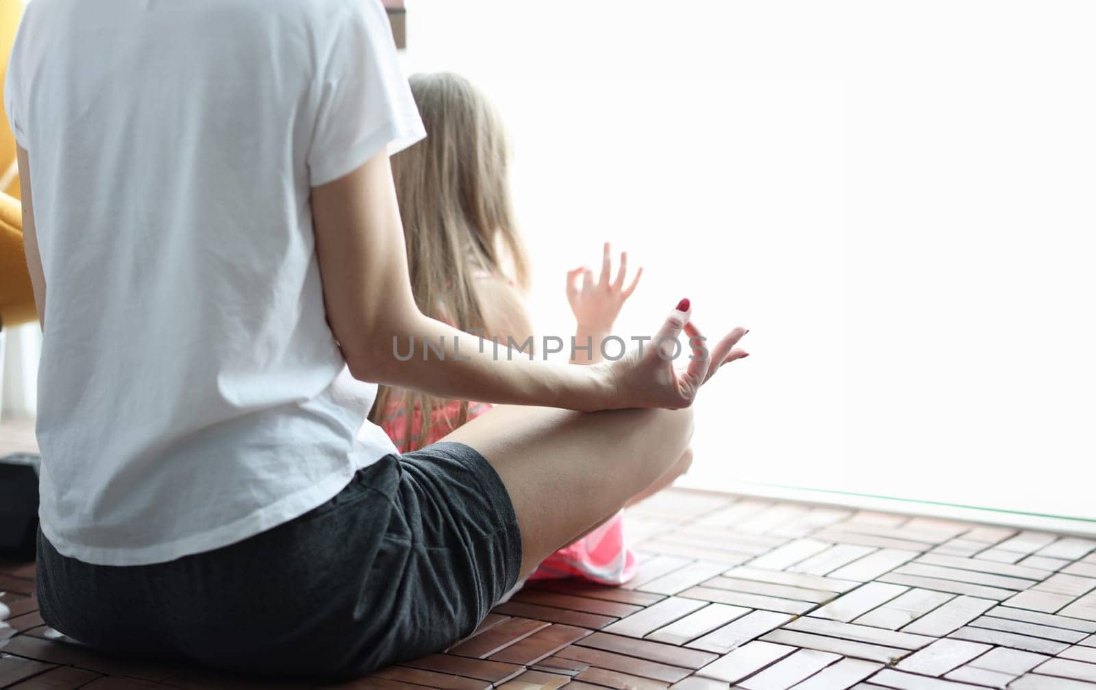 Woman with little girl sitting in lotus position on loggia closeup. Family health concept