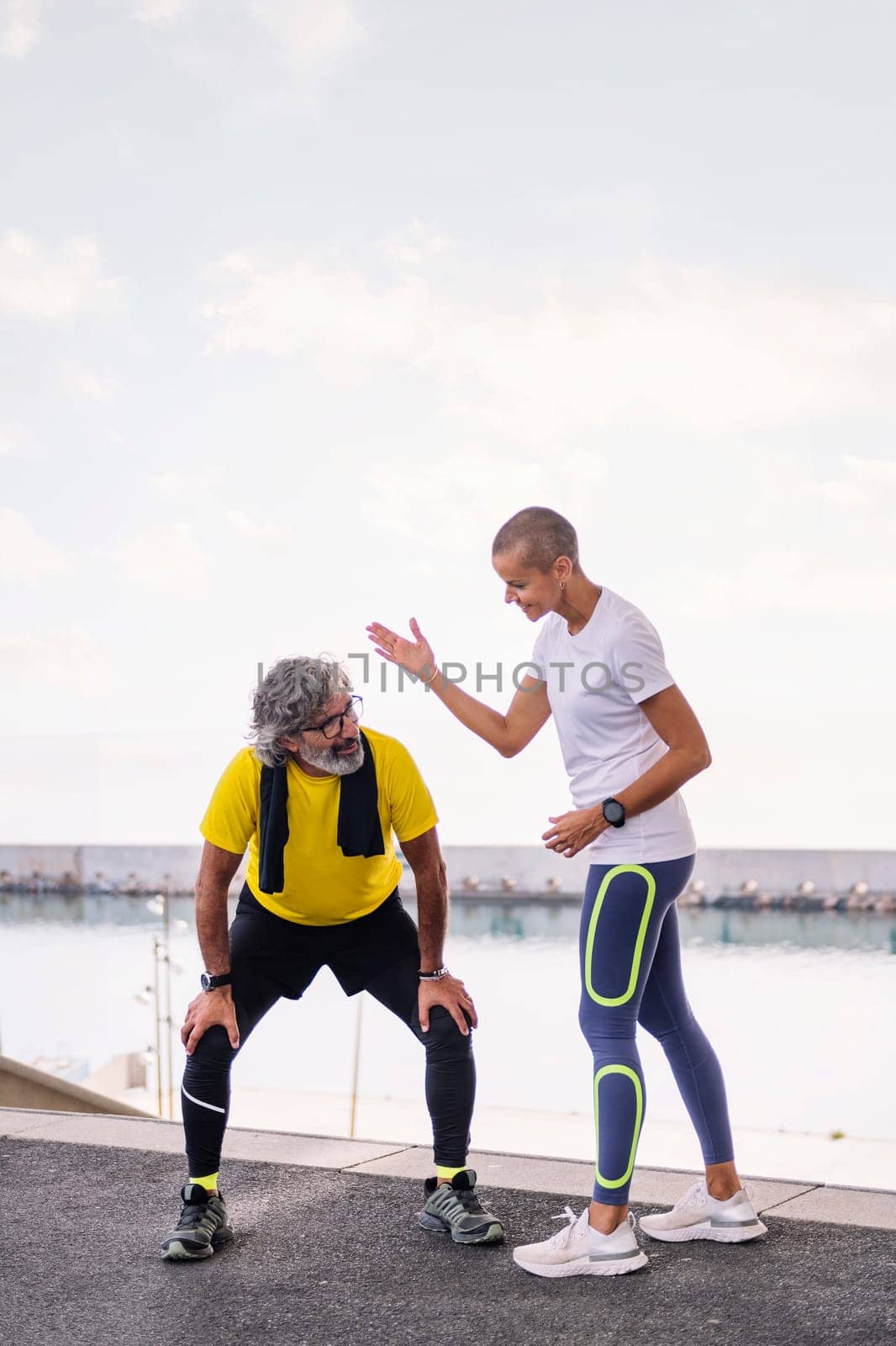 senior sports man resting exhausted next to his personal trainer after a hard workout, concept of active and healthy lifestyle in the middle age, copy space for text
