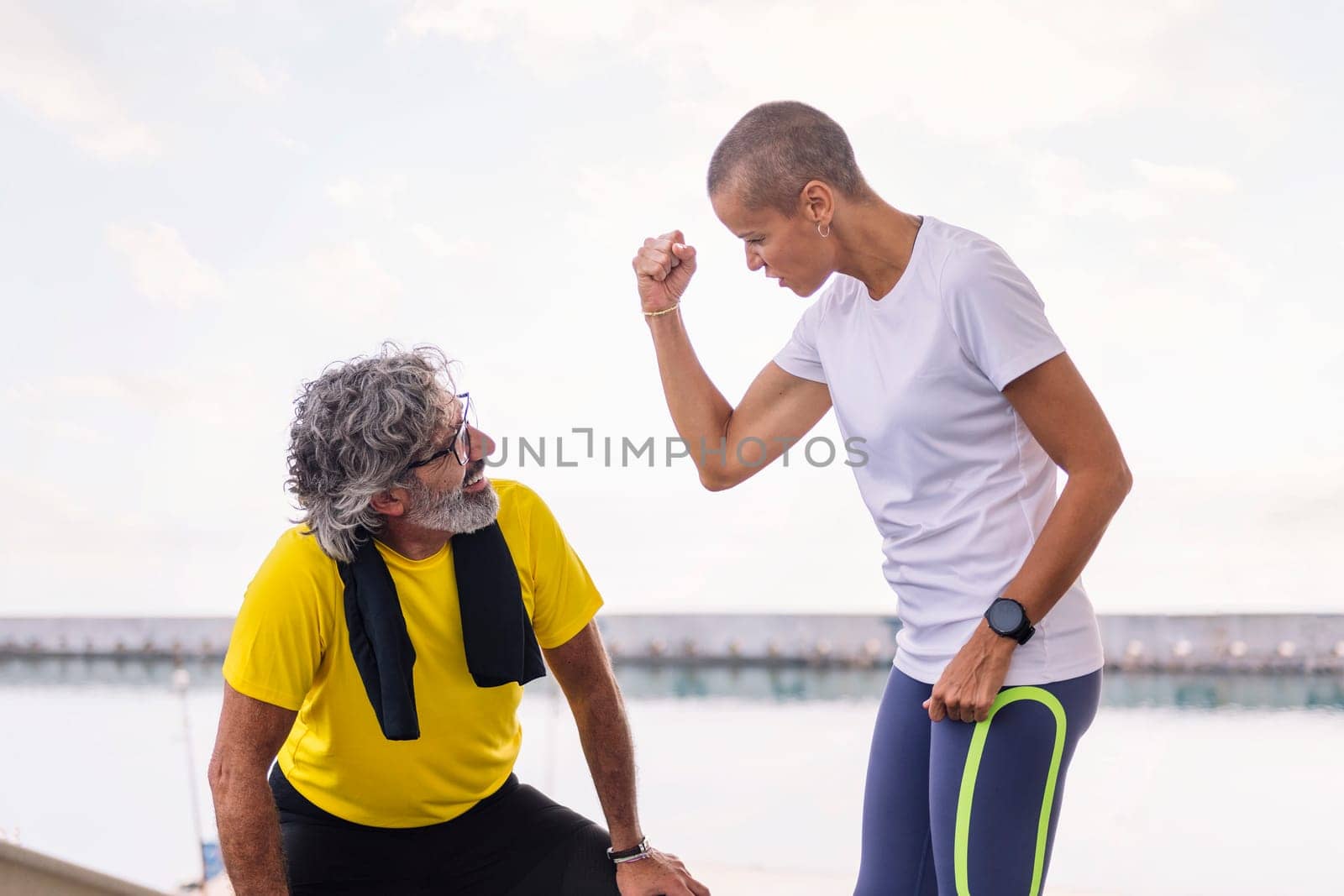 female personal trainer giving encouragement to a senior sports man, concept of active and healthy lifestyle in the middle age