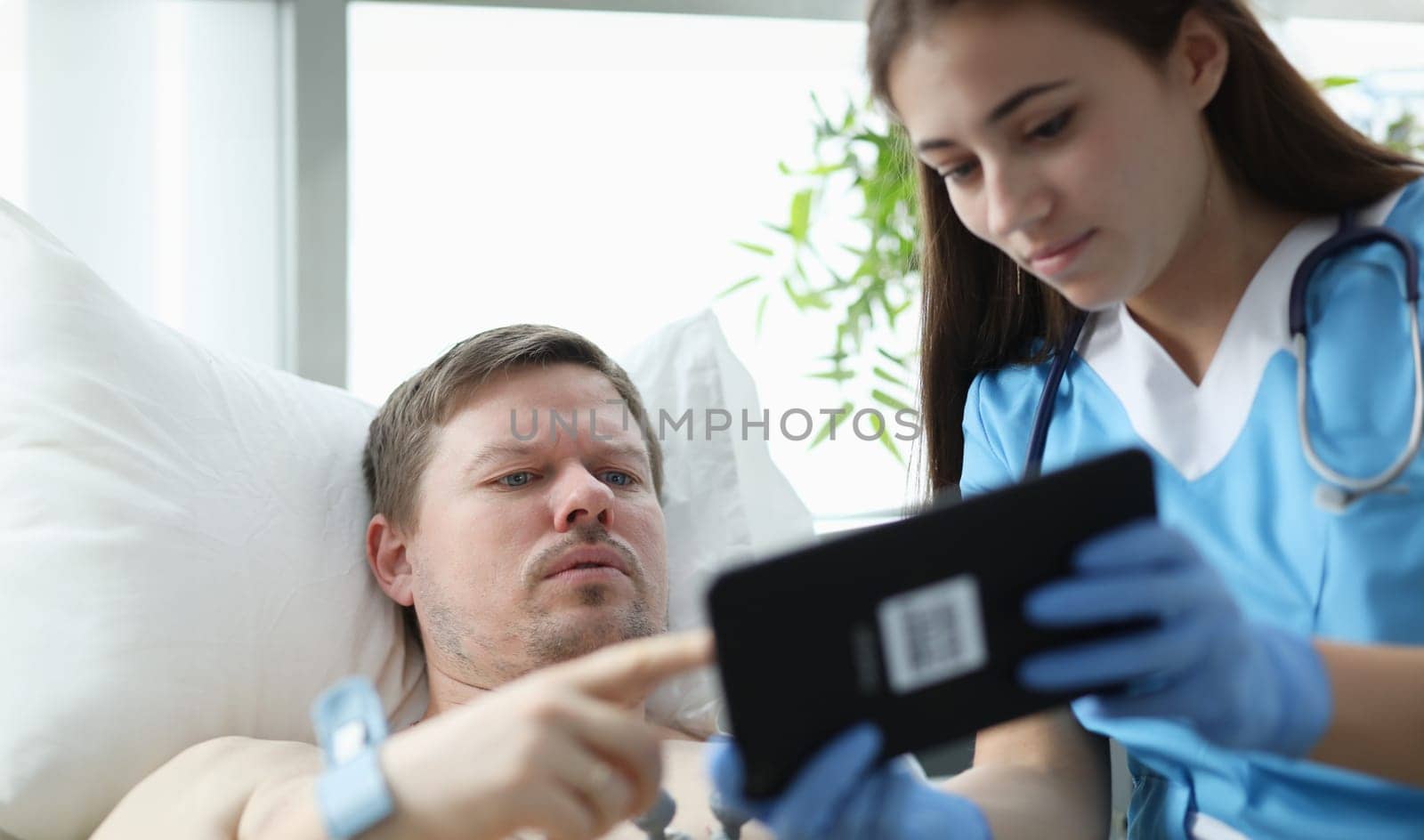 Doctor showing patient data on digital tablet in hospital. ECG diagnosis of heart disease concept