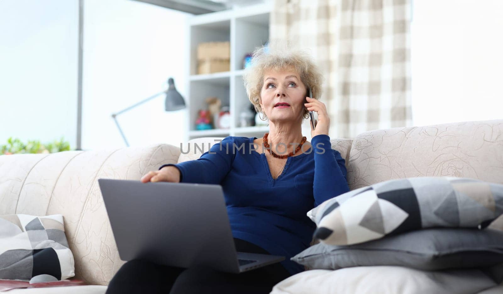 Woman talking on phone with laptop on her lap. Dont forget your parents concept