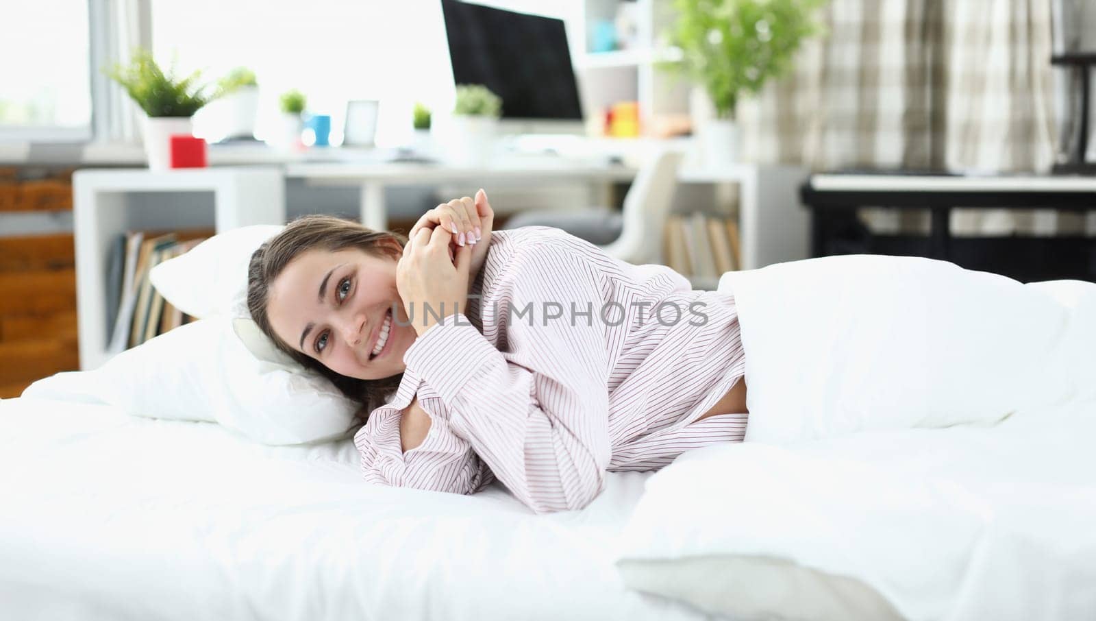 Young woman lying in bed and smiling by kuprevich
