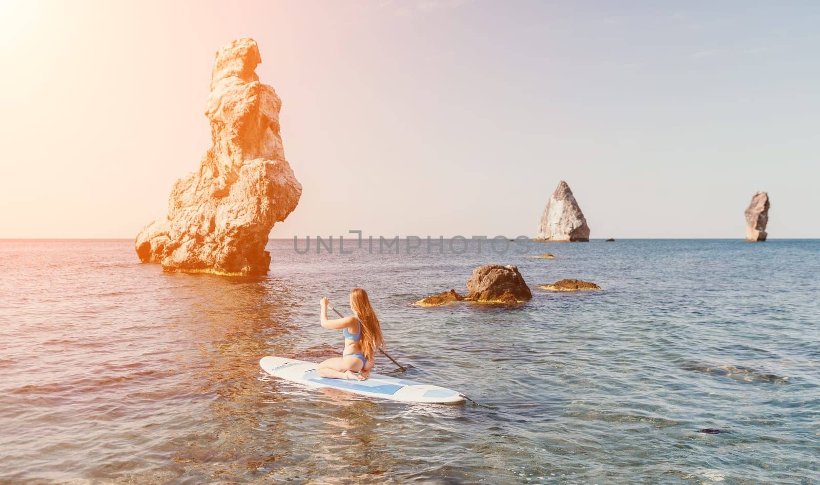 Close up shot of happy young caucasian woman looking at camera and smiling. Cute woman portrait in bikini posing on a volcanic rock high above the sea