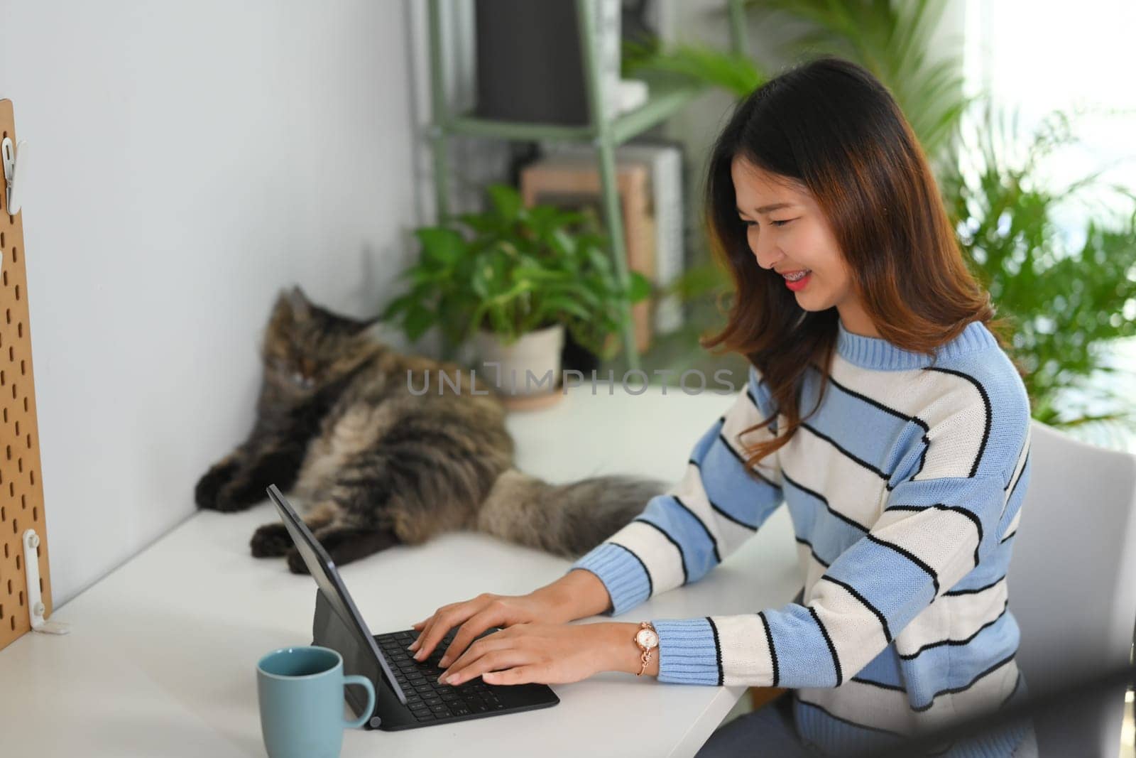 Pretty young woman in sweater working online or surfing internet on digital tablet at home