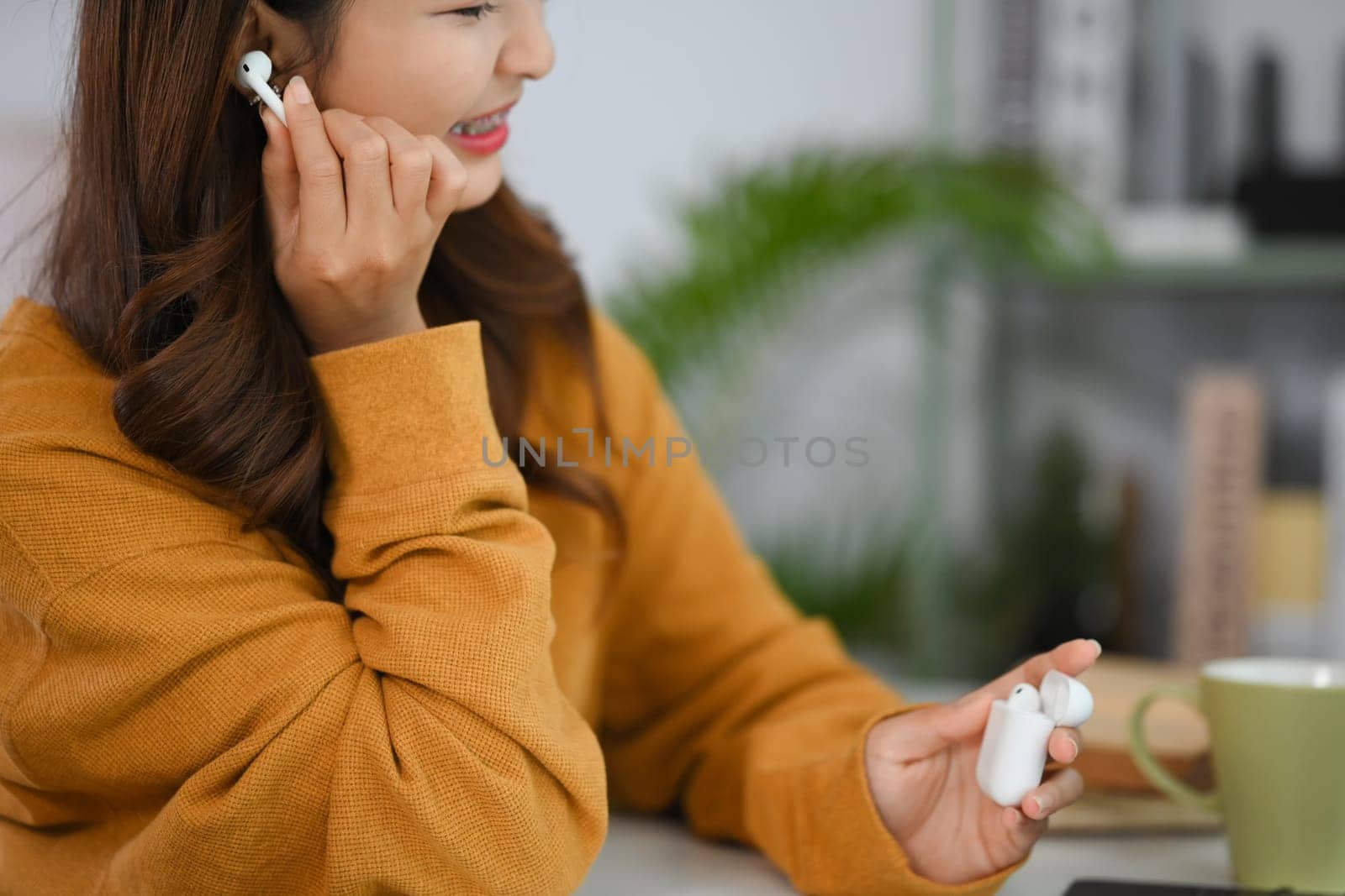 Shot happy young woman wearing earphones listening to music and resting in cozy living room