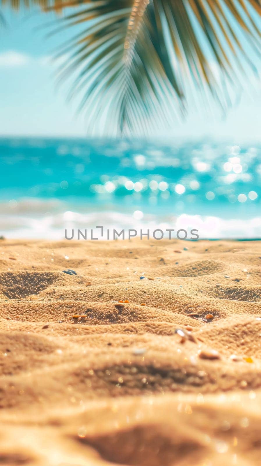 A tranquil beach scene with a foreground of golden sand leading to a softly focused turquoise sea under the shade of palm leaves, inviting relaxation and leisure by Edophoto