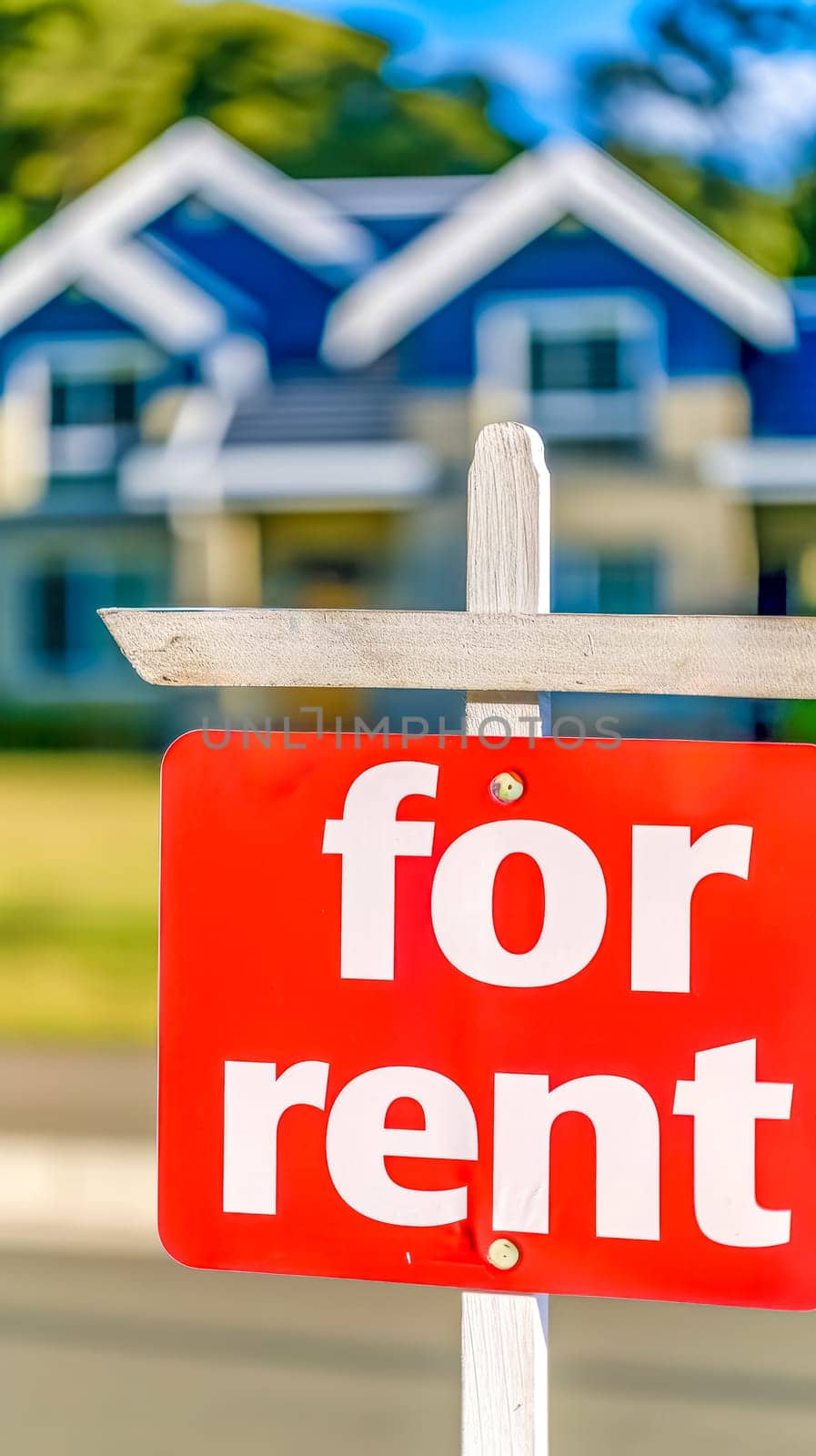 sign with the words "For Rent" prominently displayed in bold lettering, set against a background of a blurred house, creating a clear visual indication of a property space available for rent, vertical