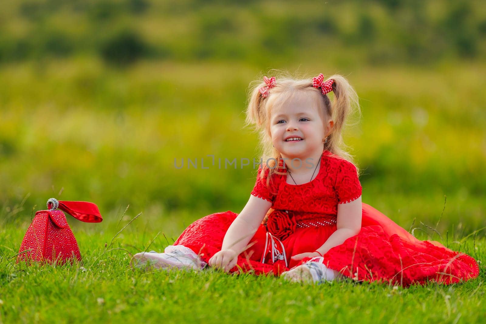 little girl in a red dress sitting on the lawn by zokov