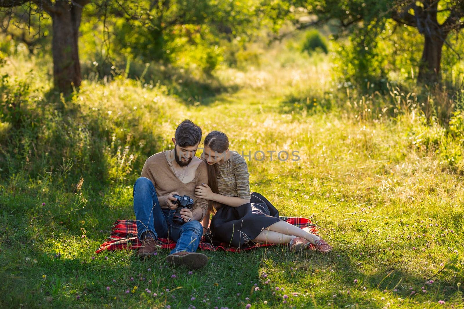 young couple relaxing in nature and looking at photos on a camera