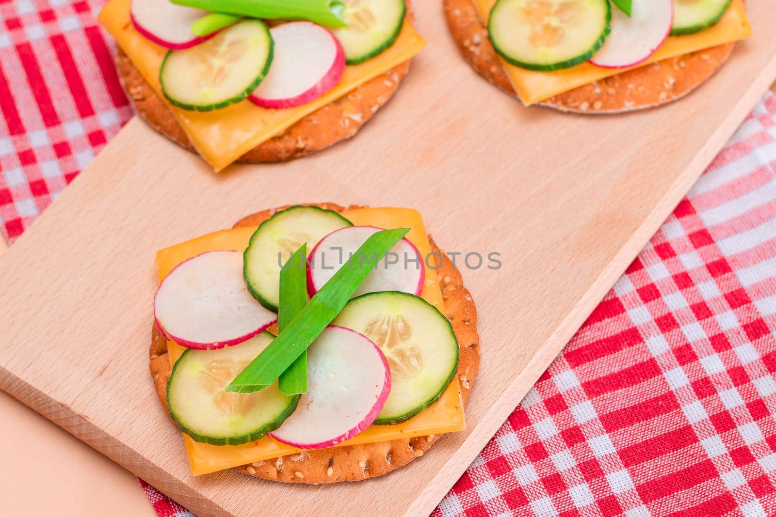 Fresh Cucumber and Radish with Green Onions and Cheese on Crispy Cracker by InfinitumProdux