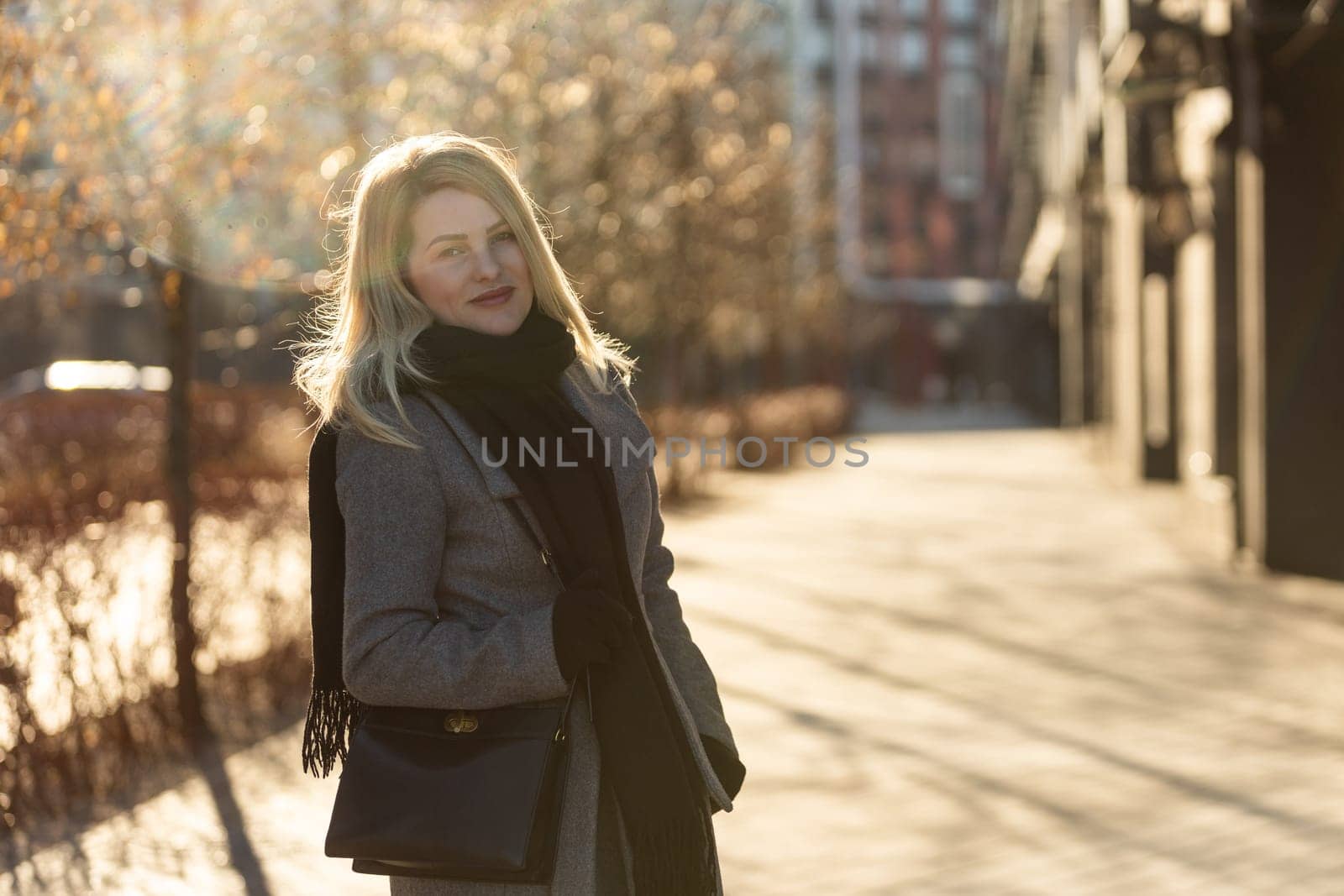 Beautiful young stylish blonde woman wearing long coat walking through the city streets. Trendy casual outfit. Street fashion. by Andelov13