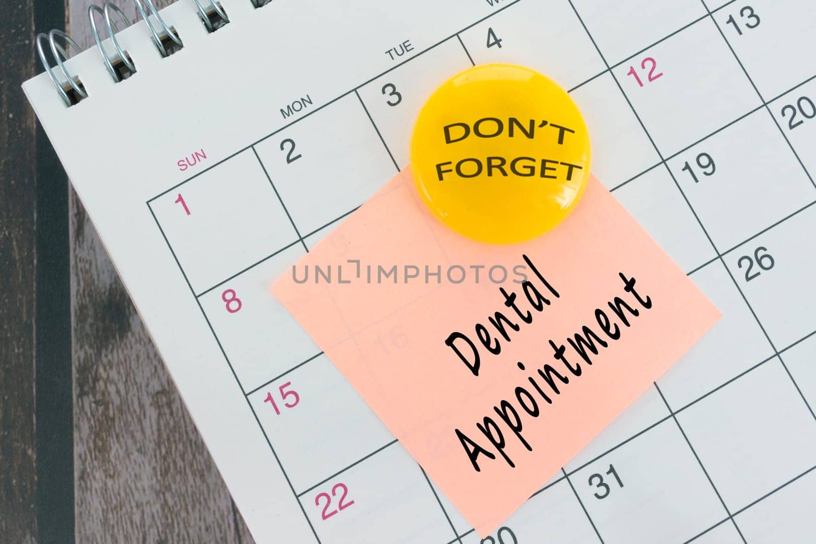 Dental Appointment text on orange paper sticky note with yellow magnet and stuck to a calendar background. Reminder concept.