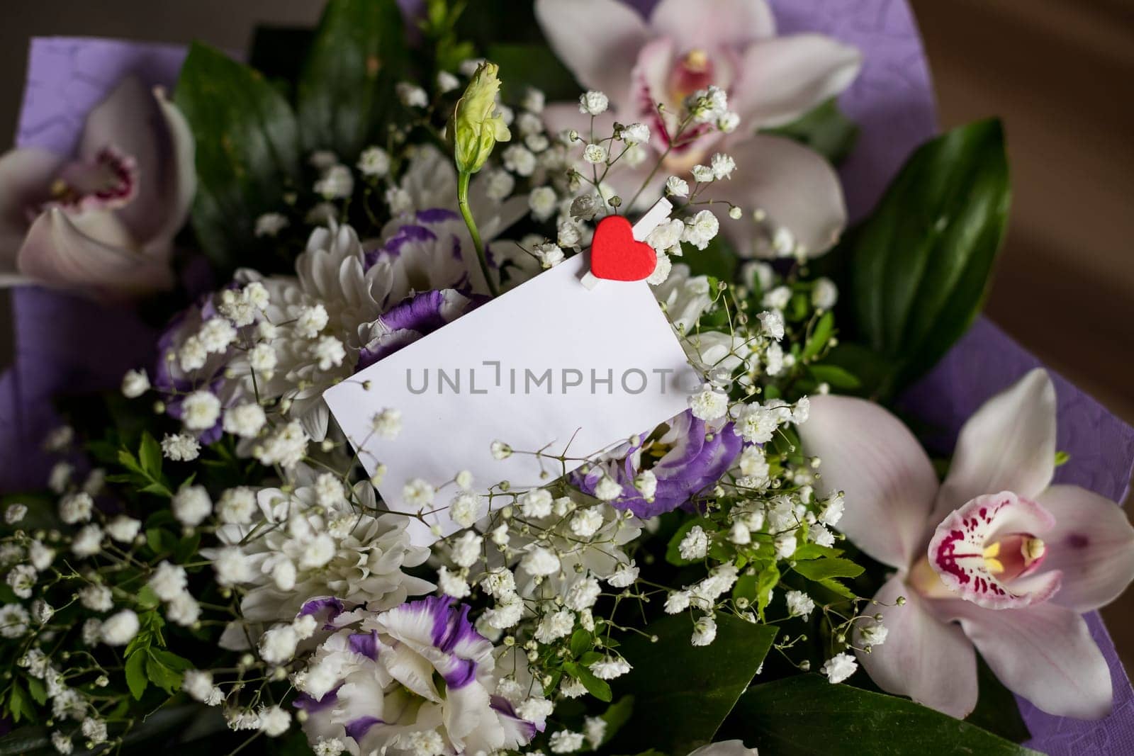 blank white greeting card with white flowers bouquet and envelope with gift box on rustic wooden background .top view. mock up