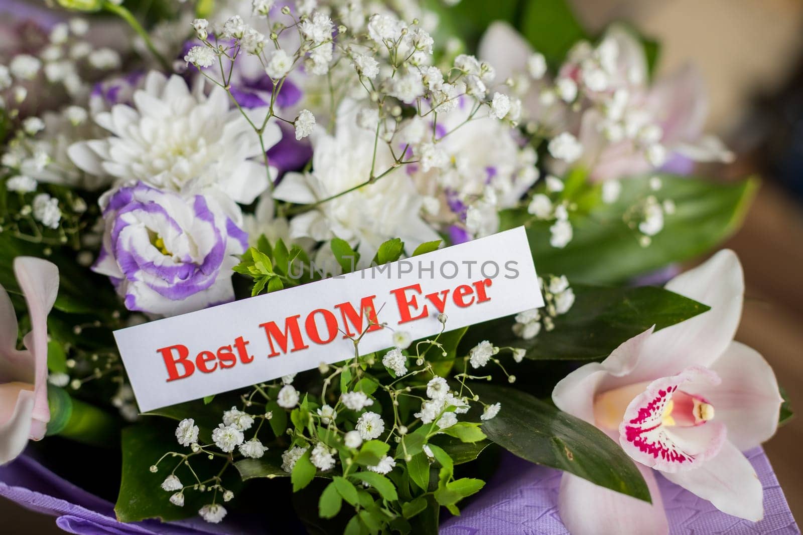 Happy Mother's Day gift, pink roses and Best Mom Ever greeting card on table.