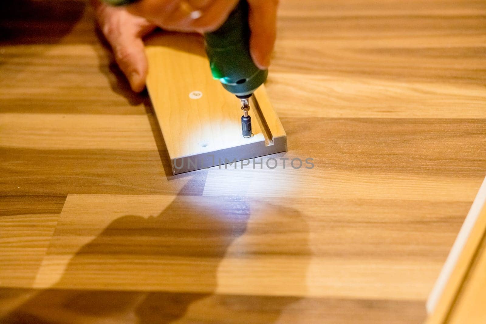 Wooden furniture assembling, woodworker screwing screws using a cordless