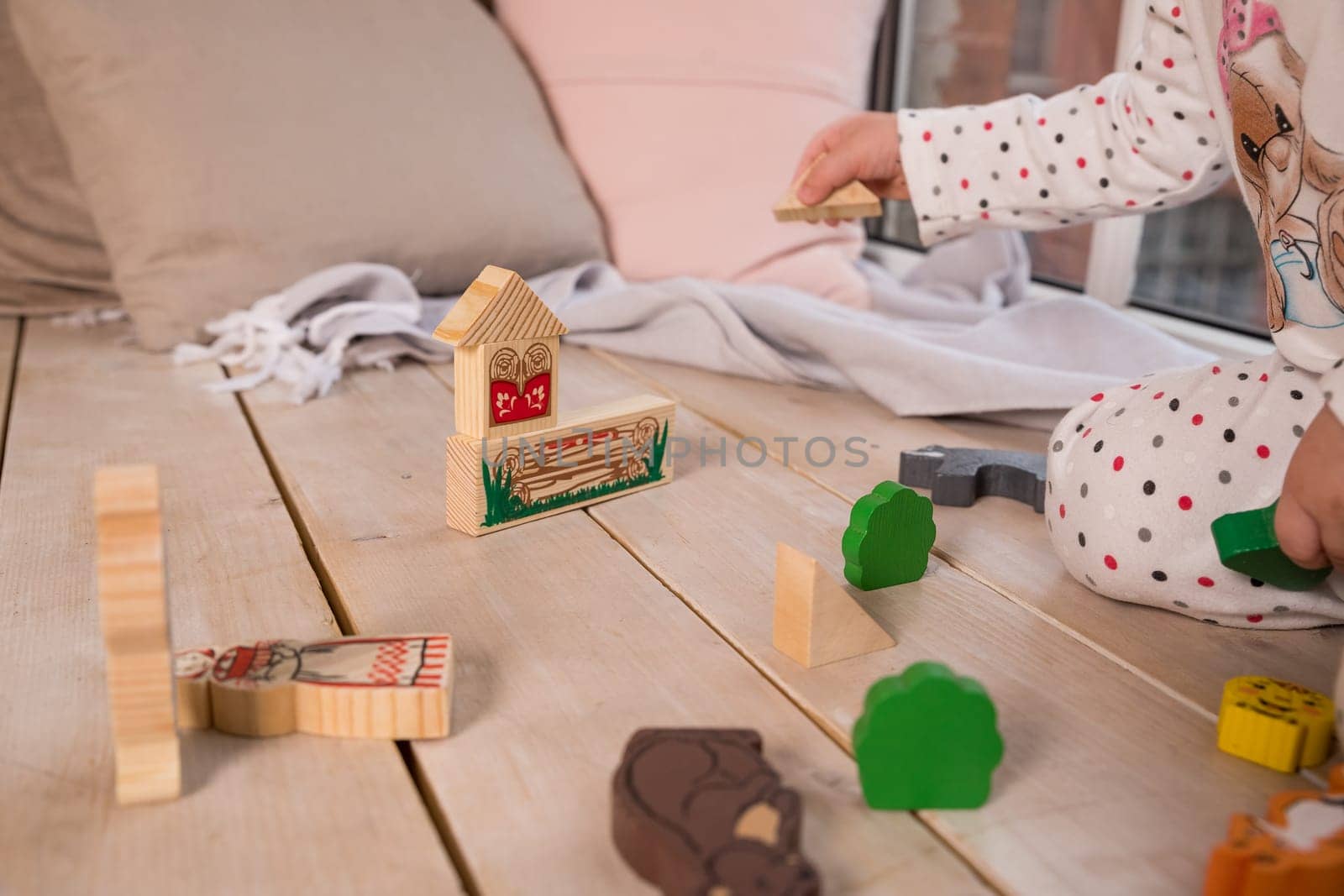 Tiny colorful wooden toy shapes and building blocks on hardwood floor.Girl play with a wooden set in their children's room on the floor. colorful blocks on the floor.cute wooden toy animal , tiny toys by YuliaYaspe1979