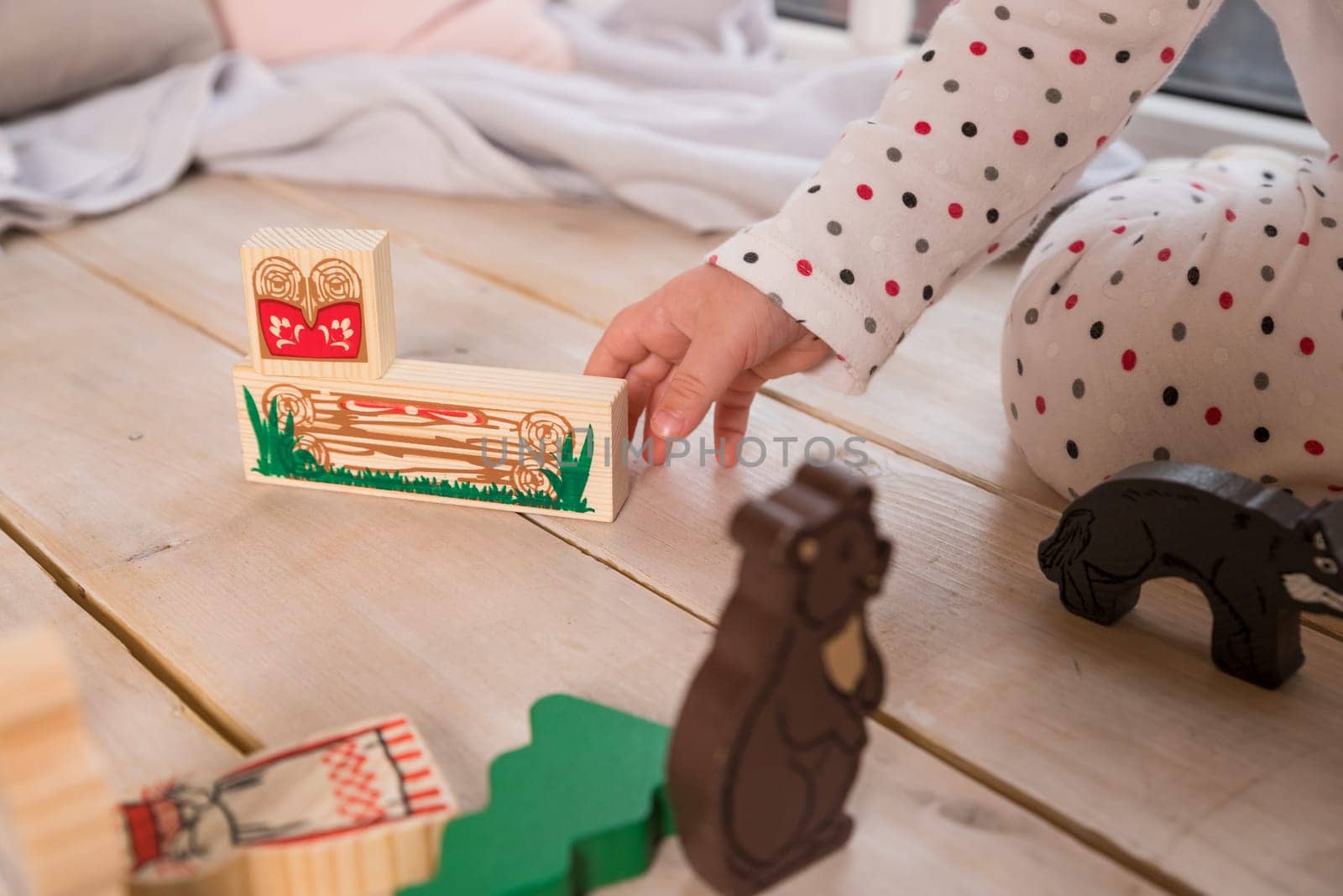 Colorful Animal Theme Urban Toys.child playing with toy ,made of wooden blocks on wooden texture floor indoors in his room. Concept of educational and developing toys for children. mini furniture toys and doll.play room at home or kindergarten by YuliaYaspe1979