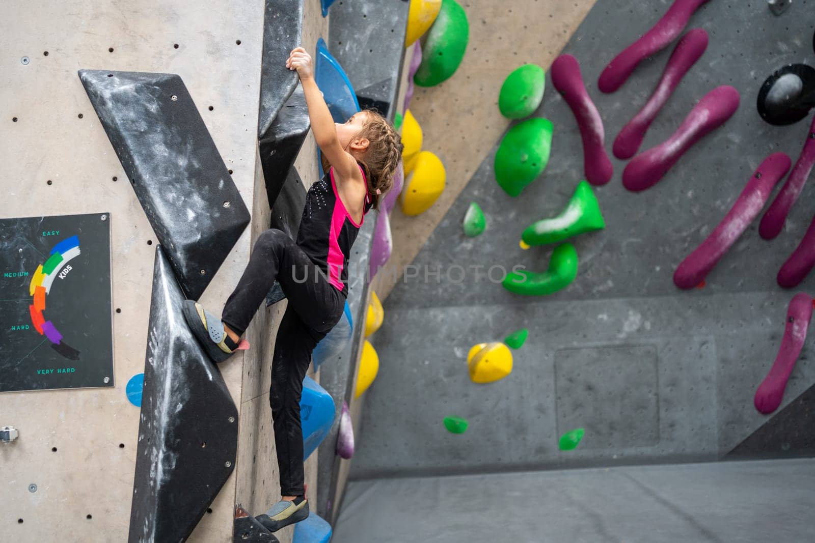 Determined girl climbing artificial wall at rock climb center by andreonegin