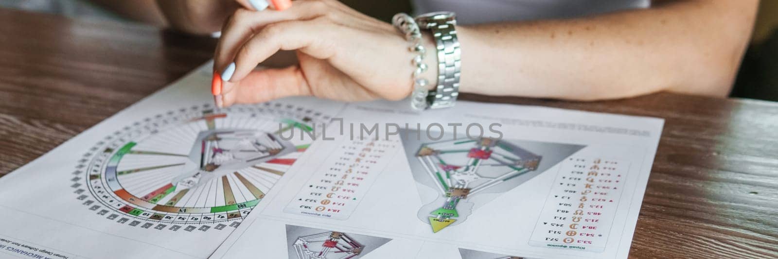 Tver, Russia - August 2, 2021. A woman in a cafe at a table is studying the design of a person. The concept of studying esoteric sciences. A bodigraph or a map of a person on an A4 sheet.