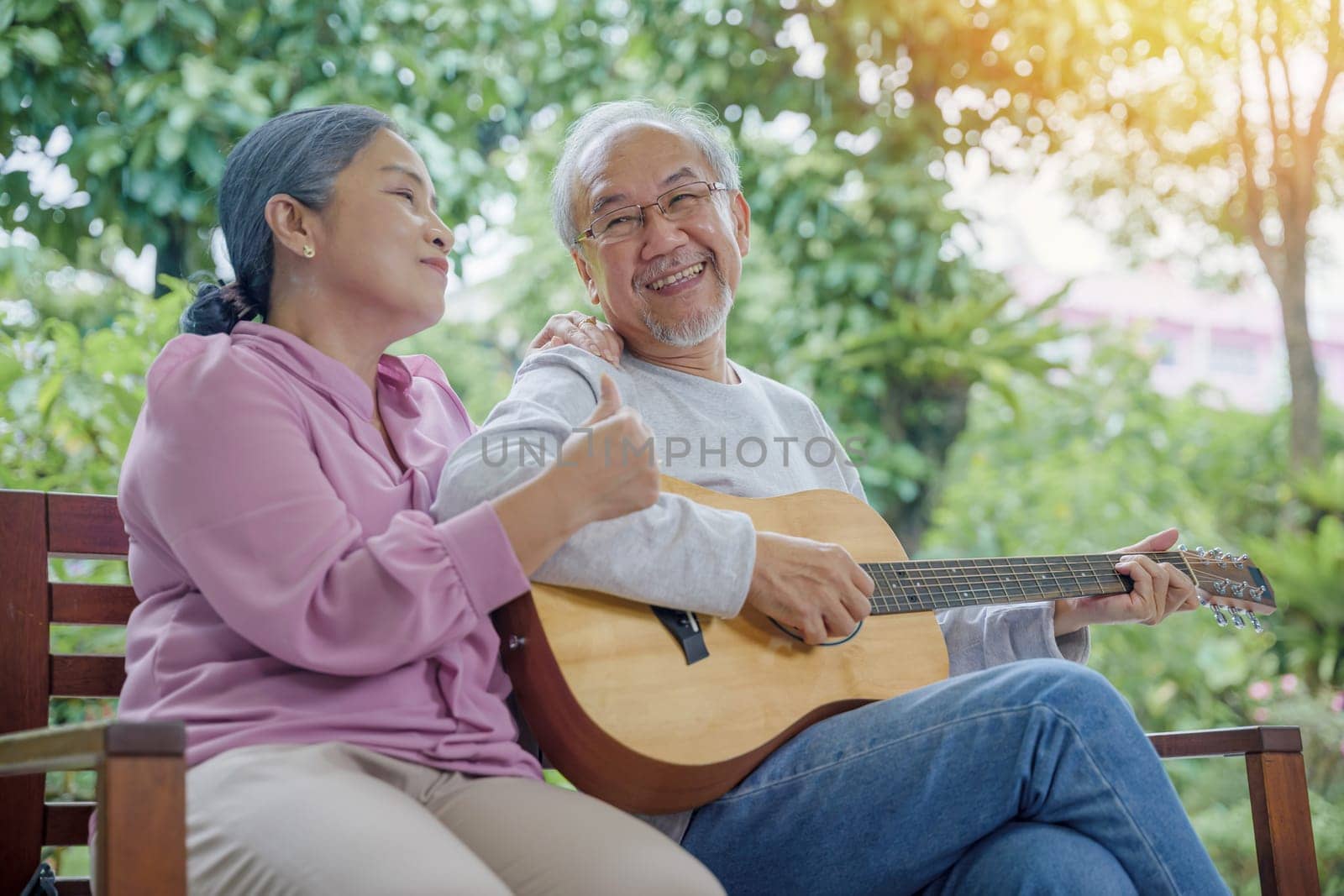 senior couple elderly man playing the guitar while his wife is singing together by Sorapop