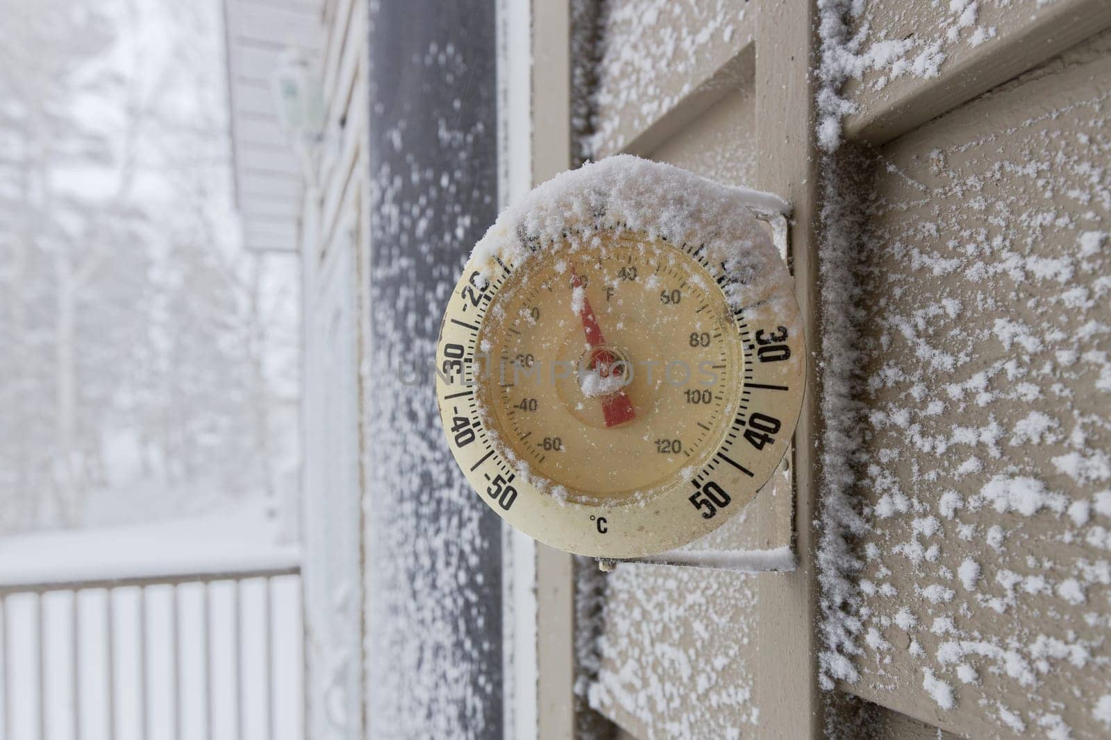 Snow Capped Thermometer Mounted on Wooden House Siding with Freezing Temperature. High quality photo
