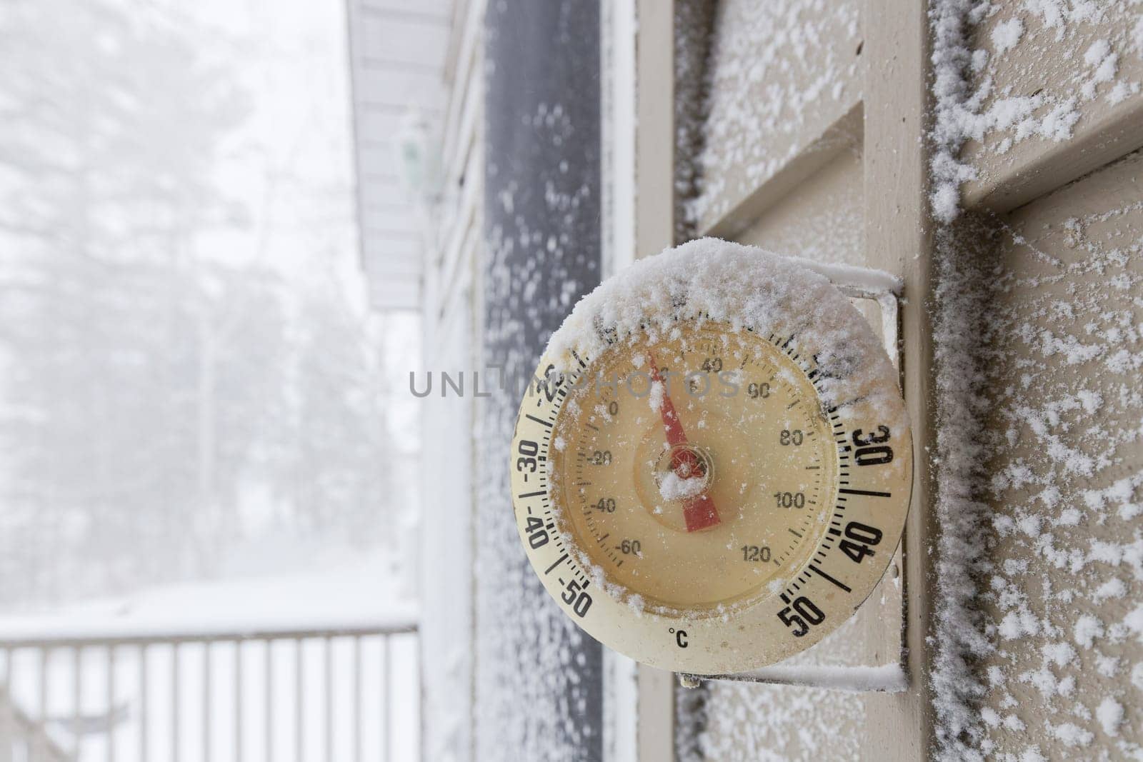 Snow Capped Thermometer Mounted on Wooden House Siding with Freezing Temperature. High quality photo