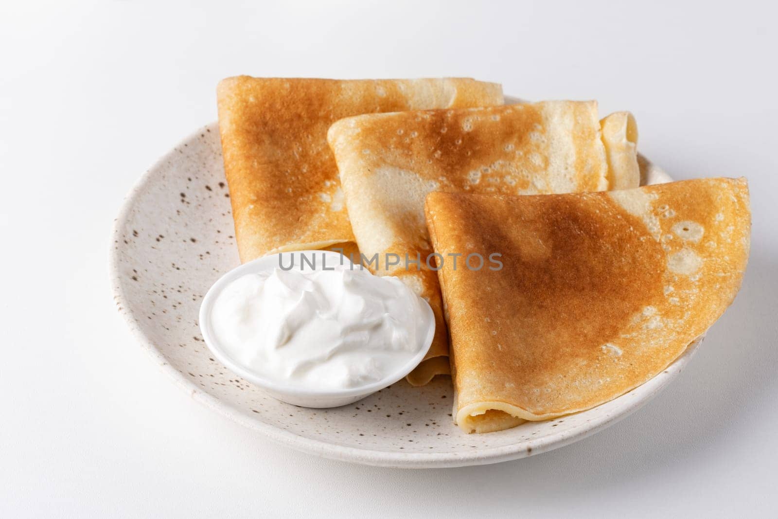 Stack of russian thin pancakes blini with fresh sour cream.