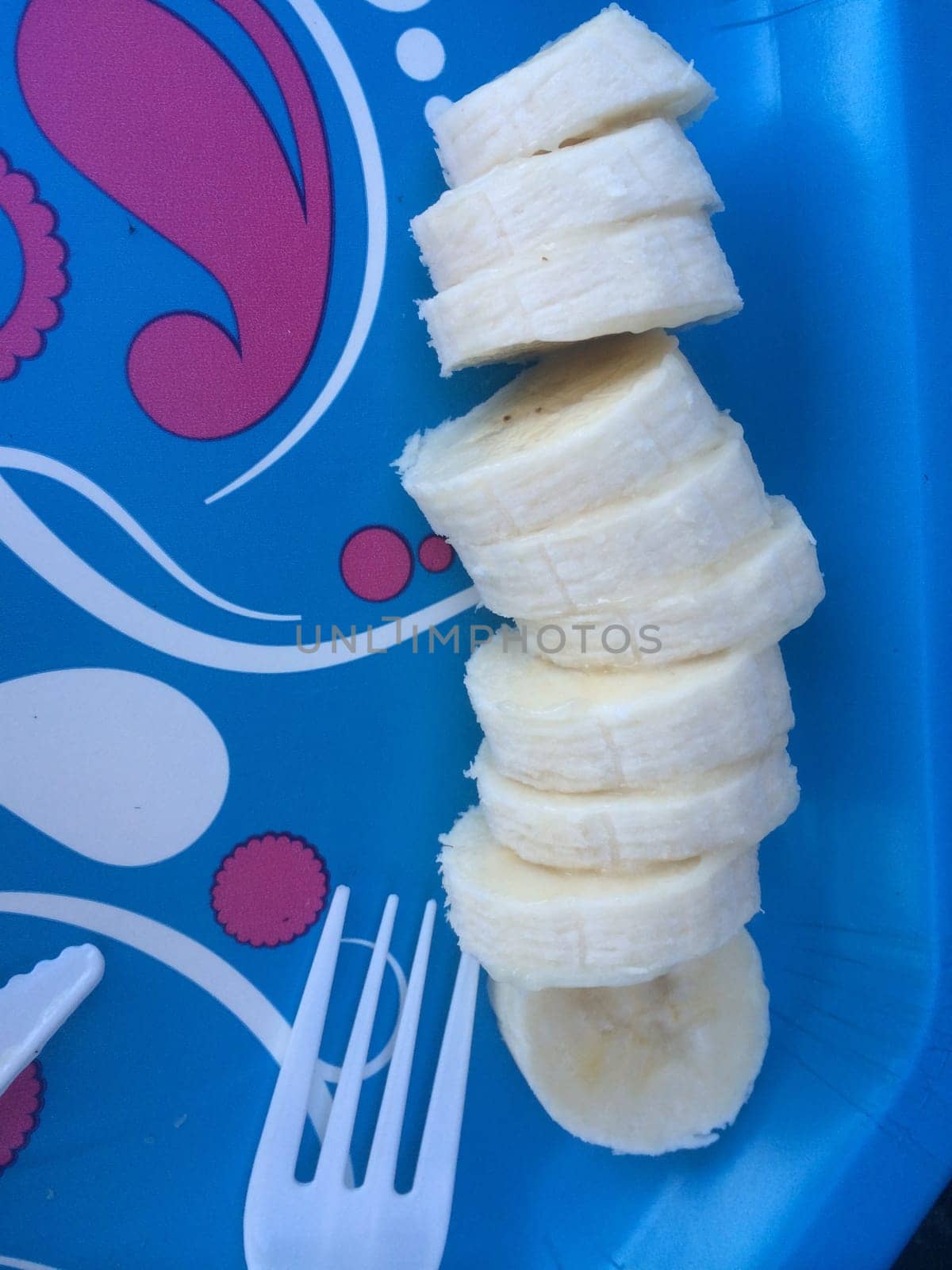 Banana Slices on Bright Colored Plate with Fork . High quality photo