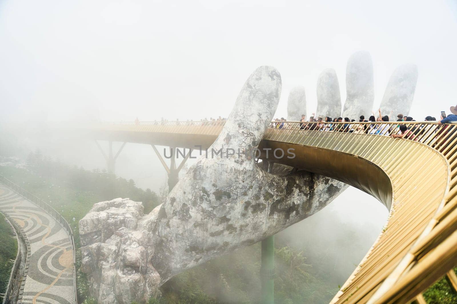 Danang, Vietnam - June 27, 2023: The Golden Bridge is lifted by two giant hands in the tourist resort on Ba Na Hill in Danang, Vietnam.